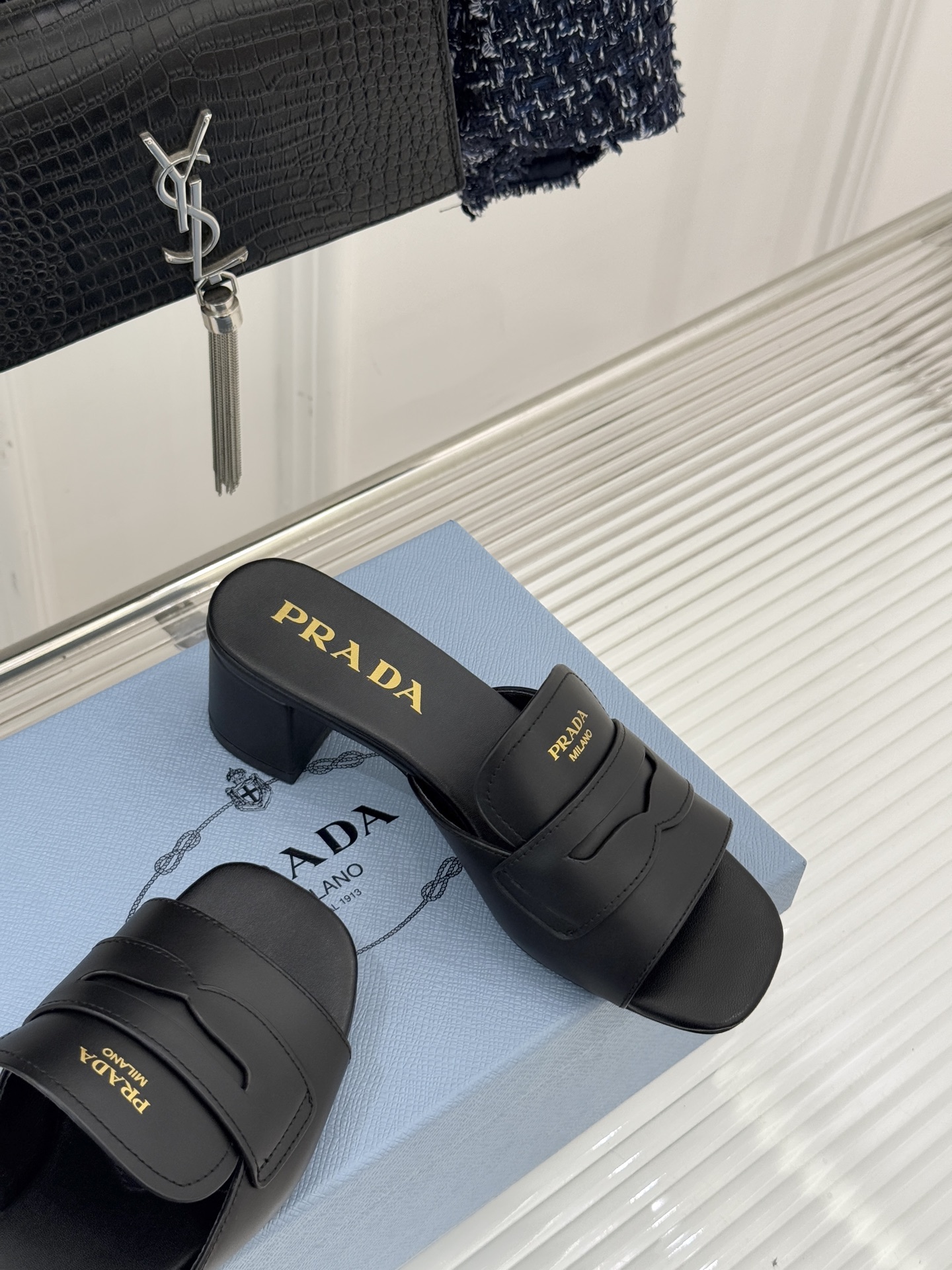 Prada/普拉达经典极简字母粗跟拖鞋循“基调之变”的设计哲思这双跟拖鞋解构奢华本质。以利落线条勾勒锥形