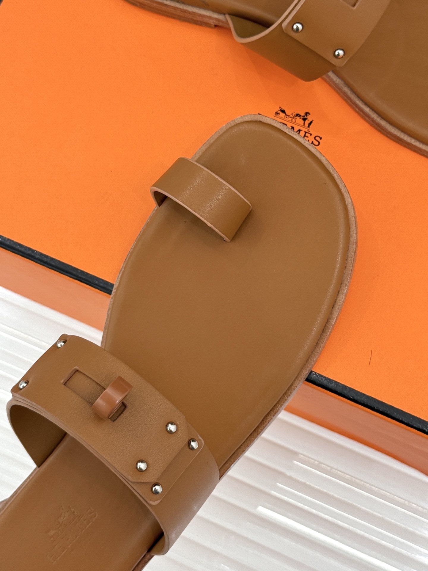 Hermès/爱马仕经典Kelly夹脚拖鞋以经典Kelly金属扣重塑夹脚拖鞋格调。甄选细腻小牛皮 触感柔