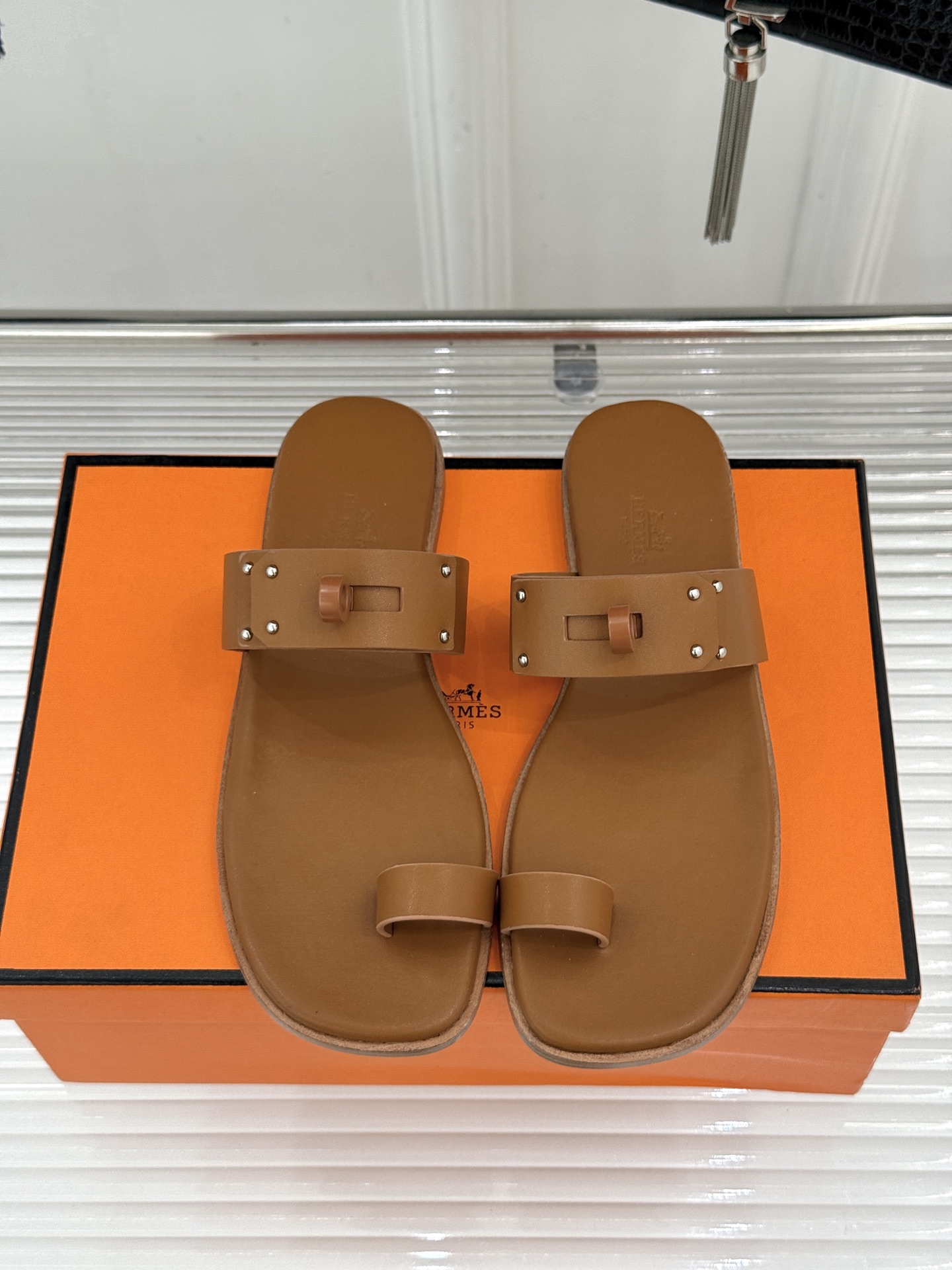 Hermès/爱马仕经典Kelly夹脚拖鞋以经典Kelly金属扣重塑夹脚拖鞋格调。甄选细腻小牛皮 触感柔