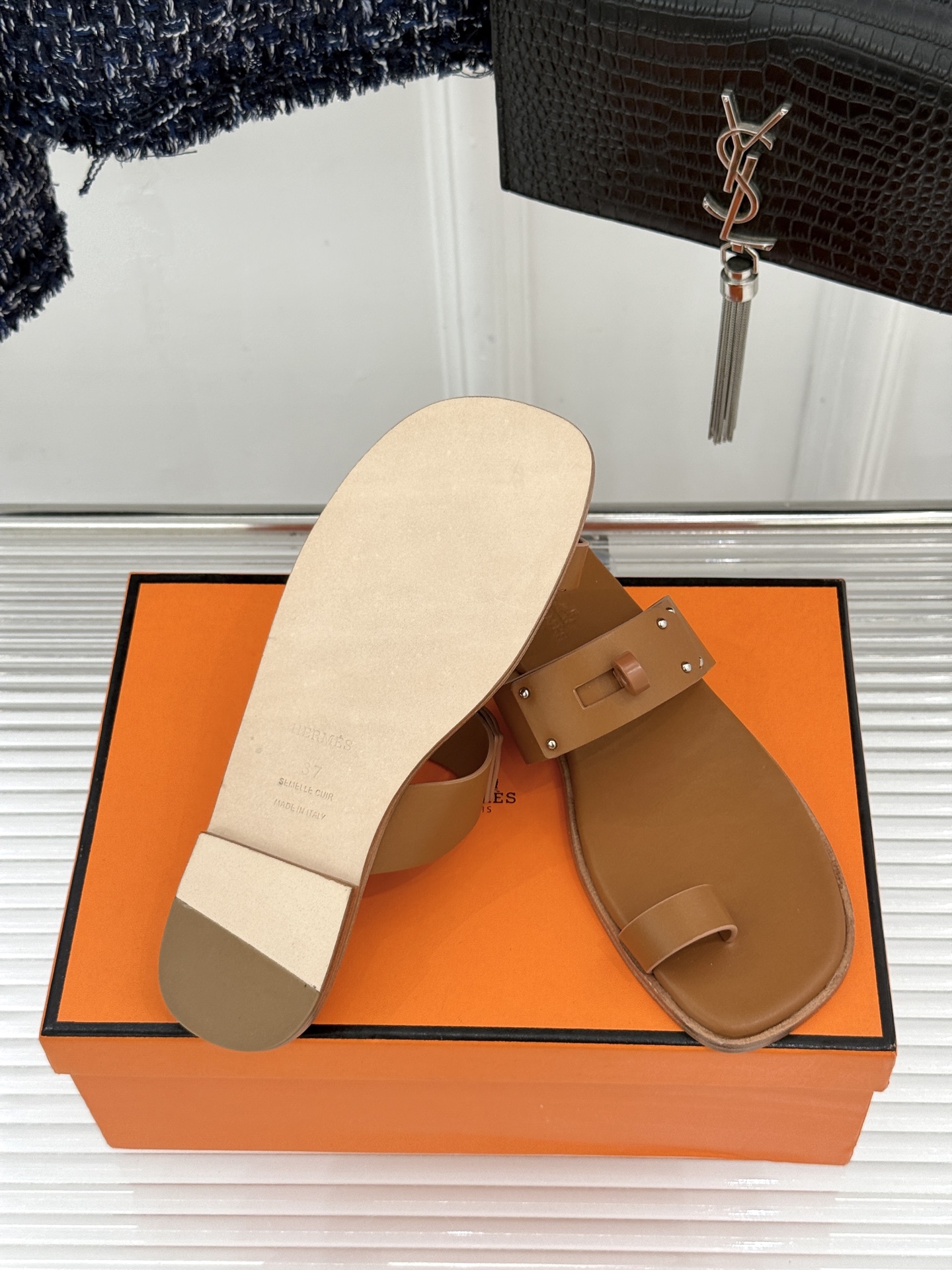 Hermès/爱马仕经典Kelly夹脚拖鞋以经典Kelly金属扣重塑夹脚拖鞋格调。甄选细腻小牛皮 触感柔