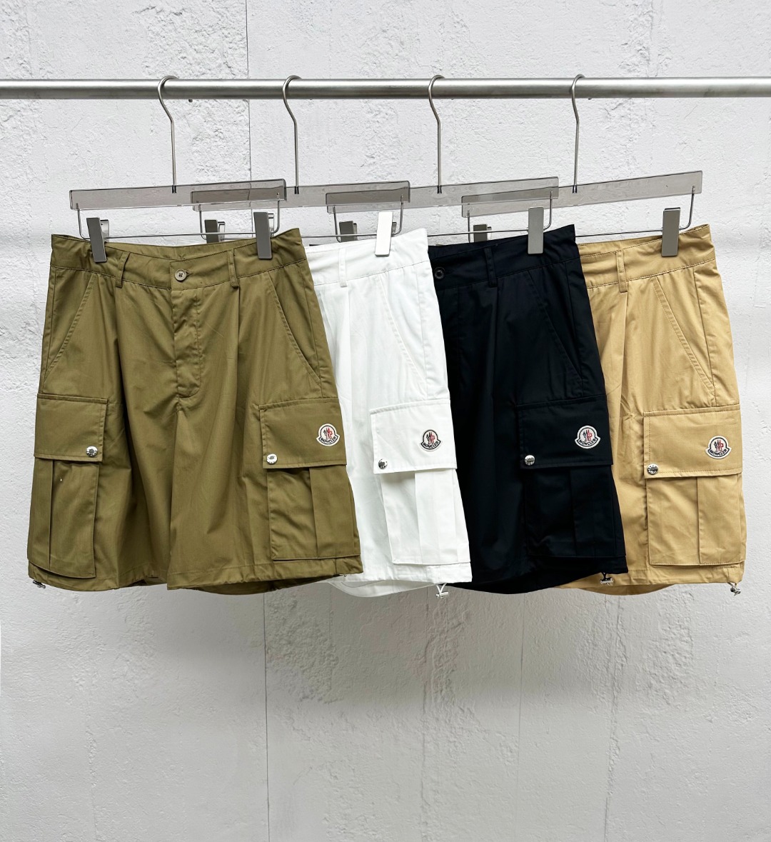NO:830498,[New Product] High-end foreign company channel goods, 2026 spring and summer new Mon*ler men's top-quality woven cotton badge flap pocket fashion loose casual cargo shorts three-quarter pants!  The shorts are made of custom-made woven cotton, which is not only comfortable and breathable, allowing you to feel cool and comfortable in the hot summer, but also has a crisp texture, making the overall lines of the shorts smooth and more quality!  The design incorporates three-dimensional pleat elements. This design cleverly conforms to ergonomics, allowing the wearer to show a dynamic and stylish posture no matter what movement he makes!  At the same time, the layering of pleats also enriches the visual expression of the shorts, making them more eye-catching!  The flap pocket design on both sides and back is not only highly practical, but its flap shape and neat stitching create a full workwear style. You can feel the toughness and uninhibitedness of these shorts at a glance!  We also spare no effort in handling details, including custom-made brand-engraved hardware button accessories. Every detail has been carefully polished and selected to ensure that it complements the overall style of the shorts!  These hardware buttons are not only strong and durable, but the brand imprinting on them also highlights the taste and style of the wearer!  The cut of the five-point shorts makes the overalls more versatile and easy to wear. Whether paired with a simple T-shirt, a casual shirt or a handsome jacket, it can be easily worn and show different fashion styles!  Color Black Green Khaki White Size M L  XL size waist 84cm - hip 112cm - front 32cm - thigh 72cm - trouser length 51cm XXL waist 88cm - hip 116cm - front 32cm - thigh 74cm - trouser length 52cm 3XL waist 92cm - hip 120cm - front 33cm - thigh 76cm - trouser length 53cm,,shorts,jackets &  coats,shirts,tees,t-shirt,19860909【新品】高端洋行渠道货,2026春夏新款Mon*ler男士顶级梭织棉布徽章翻盖口袋时尚宽松休闲工装短裤五分裤！该短裤采用客供定制梭织棉布,不仅舒爽透气,让你在炎炎夏日也能感受到清凉与舒适,而且质地挺括,使得短裤整体线条流畅,更显品质感！在设计上融入了立体褶皱元素,这一设计巧妙地贴合了人体工学,令穿着者无论在任何动作下都能展现出动感有型的身姿！同时褶皱的层次感也丰富了短裤的视觉表现,使其更加吸引眼球！两侧及后幅的翻盖口袋设计,不仅实用性强,而且其翻盖造型和工整的缝线,营造出满满的工装风格,让人一眼就能感受到这款短裤的硬朗与不羁！在细节处理上同样不遗余力,客供定制的品牌刻印五金纽扣辅料,每一个细节都经过精心打磨和挑选,确保与短裤的整体风格相得益彰！这些五金纽扣不仅坚固耐用,而且其上的品牌刻印更是彰显了穿着者的品味与格调！五分短裤的版型裁剪,使得该工装短裤在穿着上更加百搭不挑人,无论是搭配简约的T恤、休闲的衬衫还是帅气的夹克,都能轻松驾驭,展现出不同的时尚风格！ 颜色黑色 绿色 卡其色 白色 尺码M L XL XXL XXXL 尺码数据 M码腰围76cm-臀围104cm-前档30cm-大腿围68cm-裤长49cm L码腰围80cm-臀围108cm-前档31cm-大腿围70cm-裤长50cm XL码腰围84cm-臀围112cm-前档32cm-大腿围72cm-裤长51cm XXL码腰围88cm-臀围116cm-前档32cm-大腿围74cm-裤长52cm 3XL码腰围92cm-臀围120cm-前档33cm-大腿围76cm-裤长53cm,,shorts,jackets & coats,shirts,tees，t-shirt,,Men's clothing