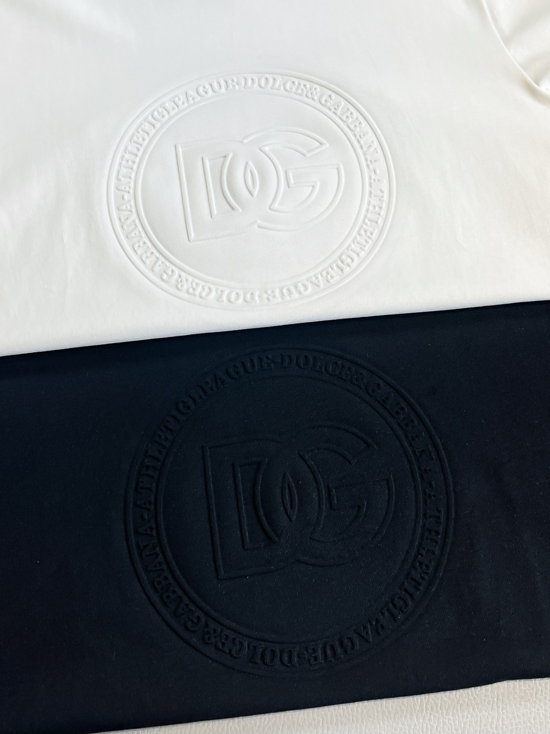 P120🍀【新品】贸易公司稀出.2025春夏Dol*e&Ga*ba*a/杜嘉班纳简约浮雕标识印花圆领短袖T恤 常规设计裁剪,兼具个性时尚范儿,与生俱来的不平凡.单穿内搭皆适宜!针织棉面料,非同一般的质感体验,号称最适合夏季的棉质面料,轻盈透气,舒适感极佳,柔软细腻更为自然.定织型的双层罗纹领口设计,平整服贴不易变形.胸口简约DG浮雕品牌LOGO标识印花依旧,营造出另类的奢华时尚气息,成为2025破茧而出的新概念.
颜色：黑色 白色
尺码：S M L  XL XXL
尺码数据：
S码:胸围102cm-肩宽46cm-衣长68cm-袖长21cm
M码:胸围106cm-肩宽47cm-衣长69cm-袖长22cm
L码:胸围110cm-肩宽48cm-衣长70cm-袖长23cm
XL码:胸围114cm-肩宽49cm-衣长71cm-袖长24cm
XXL码:胸围118cm-肩宽50cm-衣长72cm-袖长24cm
