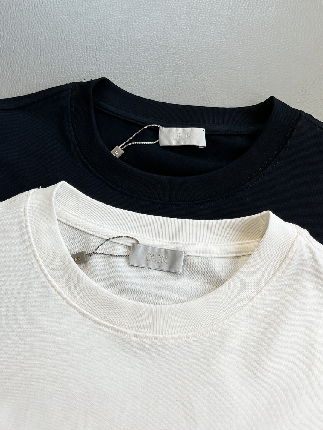 P120🍀【新品】贸易公司洋行货，重磅高级心水之物，2025春夏新款Di*r 手绘彩色标识印花男士短袖T恤。CD经典时髦字母风潮,凝聚独特技艺与灵巧的创意.简约而不失精炼风范…胸前Di*r 数码印花立体美观,后背Di*r 花卉印花,视觉效果彰显百态的奢华体验.平纹针织棉面料,细致工艺技术最高的面料标准.完美细腻的质感让着身更为舒适透气.现代休闲化裁剪工整细致,铸就独特造型魅力.
颜色：黑色 白色 
尺码：S M L XL XXL
尺码数据：
S码:胸围102cm-肩宽45cm-衣长69cm-袖长22cm
M码:胸围106cm-肩宽46cm-衣长70cm-袖长23cm
L码:胸围110cm-肩宽47cm-衣长71cm-袖长24cm
XL码:胸围114cm-肩宽48cm-衣长72cm-袖长25cm
XXL码:胸围118cm-肩宽49cm-衣长73cm-袖长26cm