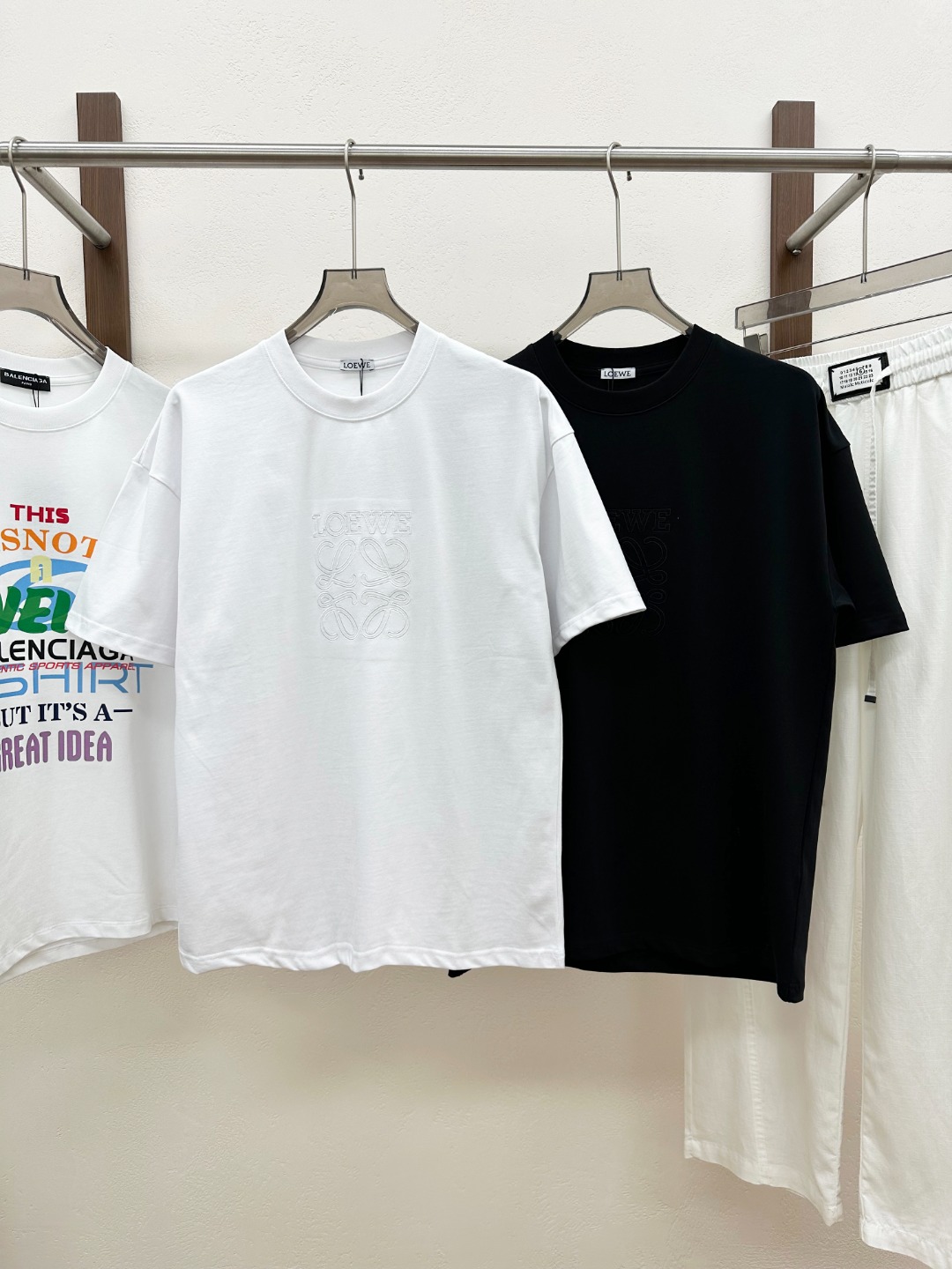 NO:830499,[New product] Rarely available through trading company channels, available simultaneously on the official website!  2026 spring and summer new Lo*we Anagram men's and women's same style jersey cotton three-dimensional logo pattern embroidered casual short-sleeved T-shirt!  This T-shirt is made of custom-made jersey cotton. The fabric feels soft and delicate, as if clouds are caressing your skin, bringing you an unparalleled comfort experience!  And it has good breathability, allowing the skin to breathe freely, keep it dry, and stay away from the troubles of stuffiness and stickiness even in the hot summer!  The three-dimensional logo pattern embroidery in the same color on the front panel is not a simple decoration, but a masterpiece of the designer's ingenuity!  The embroidery craftsmanship is exquisite, every stitch and every thread is precise, perfectly presenting the outline and details of the logo!  The matching of the same color makes the embroidery and fabric blend into one, which is not too ostentatious and obtrusive, but can also inadvertently show a low-key sense of luxury and high-end!  The frayed details on the edges of the body add a unique fashion charm to this T-shirt!  The designer cleverly uses fraying technology to create a natural and casual fraying effect on the edges of the body. This kind of detail processing not only creates a strong sense of fashion, but also makes the entire T-shirt more personalized and layered, making you stand out from the crowd!  The fitted design can perfectly fit the curves of the body. It is neither too tight to restrict your movements nor too loose to make you look bulky and dragging!  It can subtly modify your figure, show off your advantages, and at the same time cleverly cover up some minor flaws!  Color Black White Size S M L  XL code: bust 118cm - shoulder width 68.5cm - length 75cm - sleeve length 22.5cm, T-shirt, tees, t-shirt,19860909【新品】贸易公司渠道稀出,同步官网发售！2026春夏新款Lo*we Anagram男女同款平纹针织棉布立体徽标图案刺绣休闲短袖T恤衫！这款T恤采用客供定制平纹针织棉布,面料触感柔软细腻,仿佛云朵轻抚肌肤,带来无与伦比的舒适体验！而且它具有良好的透气性,即使在炎炎夏日,也能让肌肤自由呼吸,保持干爽,远离闷热与黏腻的困扰！前幅同色系立体徽标图案刺绣,这可不是简单的装饰,而是设计师匠心独运的杰作！刺绣工艺精湛绝伦,每一针每一线都精准无误,将徽标的轮廓与细节完美呈现！同色系的搭配使得刺绣与面料融为一体,既不会过于张扬突兀,又能在不经意间展现出低调的奢华与高级感！衣身边缘处的磨破细节处理,更是为这款T恤增添了一抹别样的时尚魅力！设计师巧妙地运用磨破工艺,在衣身边缘处打造出自然而随性的磨损效果,这种细节处理不仅营造出了强烈的时尚感,还让整件T恤更具个性与层次感,让你在人群中脱颖而出！合身版型设计,能够完美地贴合身体曲线,既不会过于紧绷束缚你的行动,也不会过于宽松显得臃肿拖沓！它能够巧妙地修饰身材,展现出你的优点,同时巧妙地掩盖一些小瑕疵！ 颜色黑色 白色 尺码S M L XL 尺码数据 S码:胸围106cm-肩宽56.5cm-衣长67cm-袖长19.5cm M码:胸围cm-肩宽60.5cm-衣长70cm-袖长20.5cm L码:胸围114cm-肩宽64.5cm-衣长73cm-袖长21.5cm XL码:胸围118cm-肩宽68.5cm-衣长75cm-袖长22.5cm,,T-shirt,tees，t-shirt,,Men's clothing
