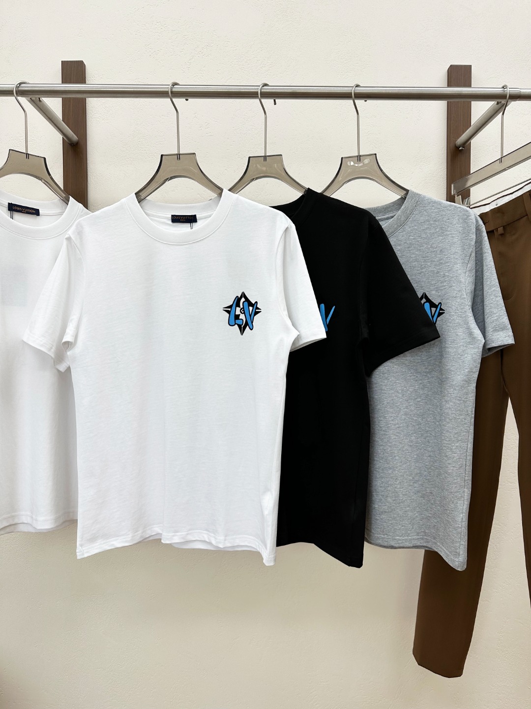 NO:849988,[New Product] 2026 spring and summer new Vden fashionable flocked embroidery logo unisex round neck short-sleeved T-shirt ~ This T-shirt is made of custom-made plain knitted cotton. After special processing, the texture of the woven cotton is tight and even, and feels as soft as a cloud!  Moreover, the fabric has excellent breathability, allowing the skin to breathe freely even in the hot summer without feeling the slightest stuffiness or discomfort!  The interesting blue and white graffiti letter logo pattern on the chest and back creates a lively yet elegant atmosphere!  The graffiti-style letter logo seems to be a vivid interpretation of street art, with an uninhibited and free atmosphere!  The designer uses top-level flocking technology, and the surface velvet is dense and neat, with good wear resistance and washability. Even after repeated washing and wearing, the pattern can still remain clear and bright, and there will be no lint loss or fading!  Fitted version design, this version is not simply about being tight or loose, but is carefully measured and repeatedly adjusted to suit the body characteristics of most people!  It can cleverly fit the curves of the body, showing off the wearer's figure advantages, while not being too tight and making people feel restricted!  Color Black White Gray Size S M L  XXL size, shoulder width 50cm - bust 120cm - length 76cm, T-shirt, tees, t-shirt,19860909【新品】2026春夏新款V登时尚植绒刺绣标识男女同款圆领短袖T恤~这款T恤选用客供定制平纹针织棉布,经过特殊的工艺处理后,织就出的棉布质地紧密、均匀,触感柔软得如同云朵一般！而且面料具有极佳的透气性,即使在炎炎夏日,也能让肌肤自由呼吸,不会感到丝毫的闷热与不适！胸前与后幅充满趣味性的蓝白涂鸦字母标识图案,营造出一种活泼而又不失高雅的氛围！涂鸦风格的字母标识,仿佛是街头艺术的生动演绎,带着一种不羁与自由的气息！设计师采用顶级植绒工艺,表面绒毛浓密而整齐,具有良好的耐磨性和耐洗性,即使经过多次洗涤和穿着,图案依然能够保持清晰、鲜艳,不会出现掉毛或褪色的现象！合身版型设计,这种版型可不是简单地追求紧身或宽松,而是经过精心测量和反复调整,以适应大多数人的身材特点！它能够巧妙地贴合身体的曲线,展现出穿着者的身材优势,同时又不会过于紧绷,让人感到束缚！ 颜色黑色 白色 灰色 尺码S M L XL XXL 尺码数据 S码肩宽46cm-胸围104cm-衣长68cm M码肩宽47cm-胸围108cm-衣长70cm L码肩宽48cm-胸围112cm-衣长72cm XL码肩宽49cm-胸围116cm-衣长74cm XXL码肩宽50cm-胸围120cm-衣长76cm,,T-shirt,tees，t-shirt,,Men's clothing