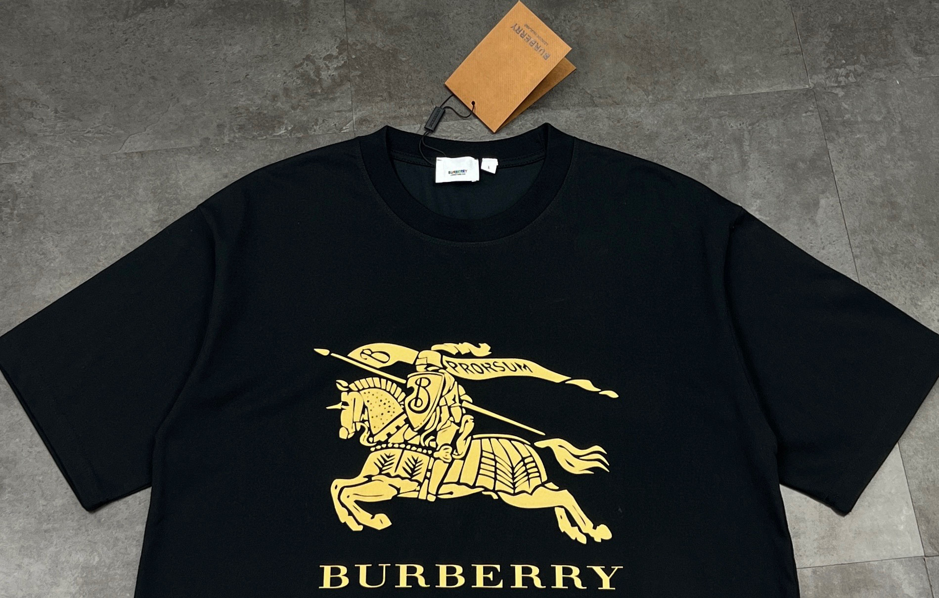 💰85
👑新款短袖上新🆕25ss夏季新品BURBERRY 🐎巴宝莉骑士tee，经典永流传，简直是时尚圈的“常青树”🌲

260g双纱面料，质感直接拉满💯  软糯又挺括，贴身穿像被云朵轻轻包裹☁️  厚度刚好，四季穿都很奈斯，不会软塌塌没型，高级感拿捏～

经典骑士图案🏇  金色印花超精致，战马奔腾的设计，自带英伦贵族气场，走在街上，回头率爆棚📸  不管是搭牛仔裤走休闲风，还是配西装裤凹轻商务造型，都能稳稳hold住，轻松拿捏各种风格切换✨

印花工艺也很绝，久洗不易脱落、开裂，经得住时间考验⌛️  就像巴宝莉的品牌魅力，历久弥新，穿个几年依旧是衣柜里的“宝藏单品”💎

喜欢经典款、追求品质的宝子，别错过！穿上它，你就是行走的时尚教科书，把高级感焊在身上～

颜色：黑色/白色
尺码：M  L  XL  2XL

M：胸围54  肩宽52   衣长70   袖长22.5
（建议身高170-173厘米）
（建议体重110-135斤）
L：胸围 56  肩宽54   衣长72  袖长23
（建议身高173-175厘米）
（建议体重135-160斤）
XL：胸围58  肩宽56  衣长74  袖长23.5
（建议身高175-180厘米）
（建议体重160-185斤）
2XL：胸围60  肩宽58  衣长76   袖长24 
（建议身高180-185厘米）
（建议体重185-210斤）
👑温馨提示:手工平铺测量，误差在1-2cm内属于正常范围
