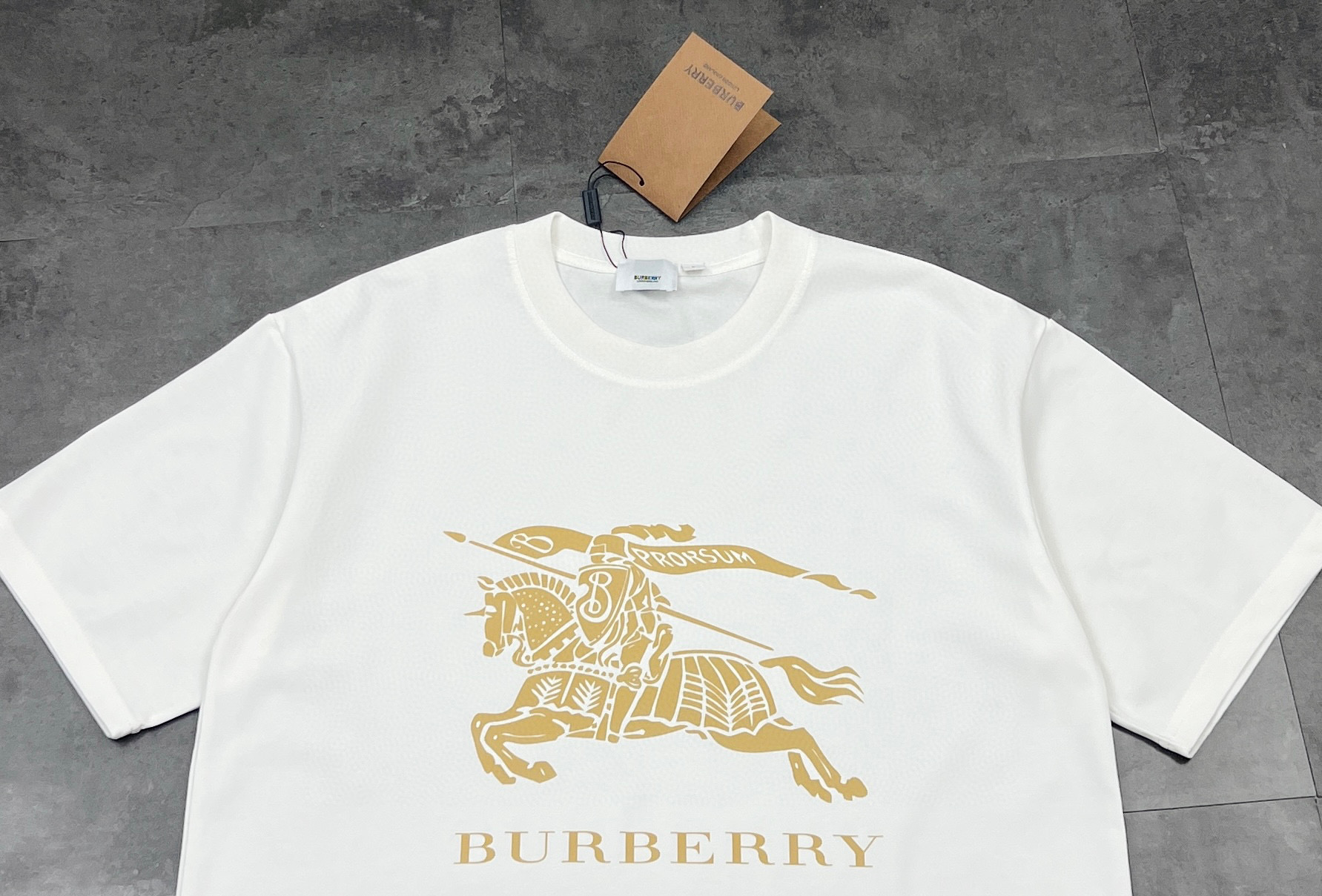 💰85
👑新款短袖上新🆕25ss夏季新品BURBERRY 🐎巴宝莉骑士tee，经典永流传，简直是时尚圈的“常青树”🌲

260g双纱面料，质感直接拉满💯  软糯又挺括，贴身穿像被云朵轻轻包裹☁️  厚度刚好，四季穿都很奈斯，不会软塌塌没型，高级感拿捏～

经典骑士图案🏇  金色印花超精致，战马奔腾的设计，自带英伦贵族气场，走在街上，回头率爆棚📸  不管是搭牛仔裤走休闲风，还是配西装裤凹轻商务造型，都能稳稳hold住，轻松拿捏各种风格切换✨

印花工艺也很绝，久洗不易脱落、开裂，经得住时间考验⌛️  就像巴宝莉的品牌魅力，历久弥新，穿个几年依旧是衣柜里的“宝藏单品”💎

喜欢经典款、追求品质的宝子，别错过！穿上它，你就是行走的时尚教科书，把高级感焊在身上～

颜色：黑色/白色
尺码：M  L  XL  2XL

M：胸围54  肩宽52   衣长70   袖长22.5
（建议身高170-173厘米）
（建议体重110-135斤）
L：胸围 56  肩宽54   衣长72  袖长23
（建议身高173-175厘米）
（建议体重135-160斤）
XL：胸围58  肩宽56  衣长74  袖长23.5
（建议身高175-180厘米）
（建议体重160-185斤）
2XL：胸围60  肩宽58  衣长76   袖长24 
（建议身高180-185厘米）
（建议体重185-210斤）
👑温馨提示:手工平铺测量，误差在1-2cm内属于正常范围
