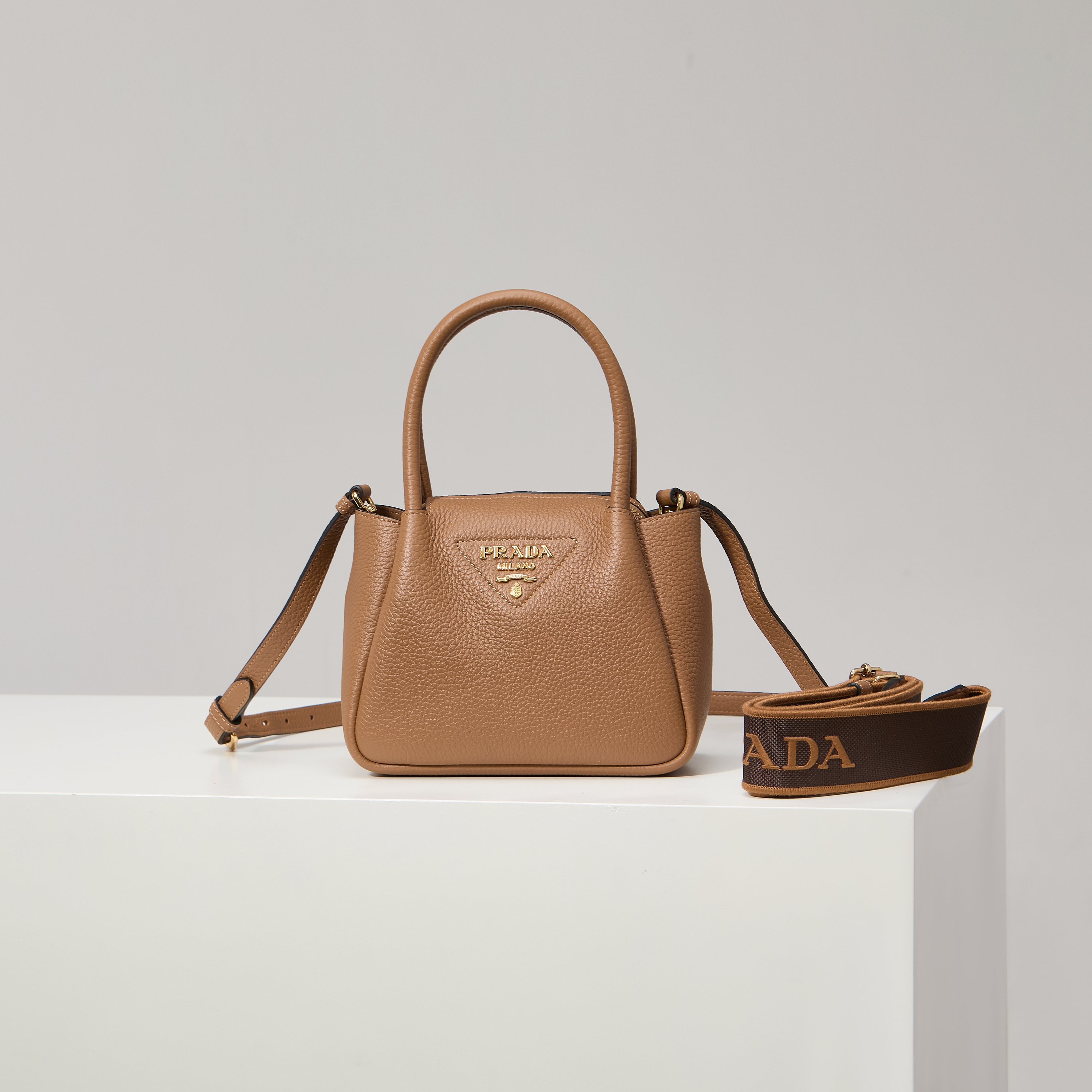 NO:602392,[Special Original] The new mini shoulder bag 1BA362/caramel color/(double strap) from the counter has arrived. This contemporary exquisite leather handbag shows natural texture and uses reverse stitching design to create a soft and round shape. It is compact and can be carried by hand or carried on the back with a detachable shoulder strap. The shape is versatile and refined and elegant. Detachable and adjustable leather shoulder strap, length 95 cm. Maximum length 107 cm - Minimum length 56 cm - Maximum vertical length 56 cm -  Minimum drop length 35cm, metal hardware accessories, metal letter logo on the front, zipper bag opening, with 3 compartments, great texture. I fell in love with it at first sight. Ladies, hurry up and get it. Size 18*19.5*9cm, Prada [price in quantity], prada, shoulder bags19860909【特级原厂】专柜新款迷你单肩包1BA362/焦糖色/（双肩带）到货这款当代精致皮革手袋呈现天然纹理,以反向缝线设计打造柔软圆润的造型.体量小巧,既可手提,又可配上可拆卸肩带后肩背,造型百变,精致优雅. 可拆卸可调式皮革肩带,长度95厘米.最大长度107厘米 - 最小长度56厘米 - 最大垂长56厘米 - 最小垂长35厘米,金属五金配件,正面金属字母徽标,拉链包口,配3个隔层,质感超赞 一眼就爱上了 女士们赶紧下手吧 尺寸18*19.5*9cm,普拉达【跑量价】,prada,shoulder bags,Bag