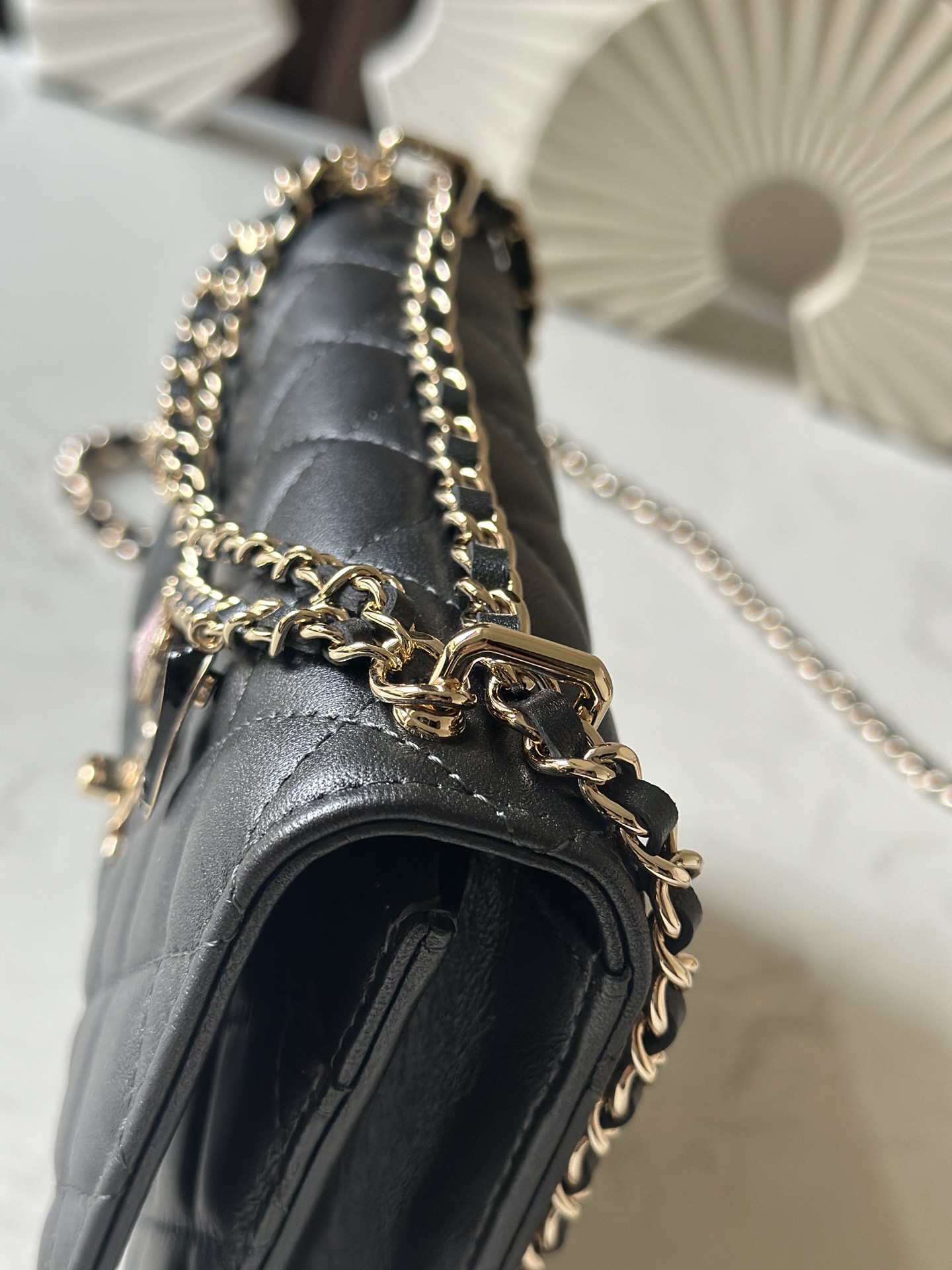 p670。chane12025春夏
chanel 太懂少女心!2025年春夏的轻巧俏
皮又精致，采用珠面小羊皮，搭配经典的菱格纹和金色 clogo。手袋上还有一个粉色心形，搭配金色链条，让人一见倾心，入坑!还可
以侧背或肩背，容量也不错，纸巾都可以放进去，通勤日常都ok
款号：66051 黑色
尺寸:19.5*13*3.5
