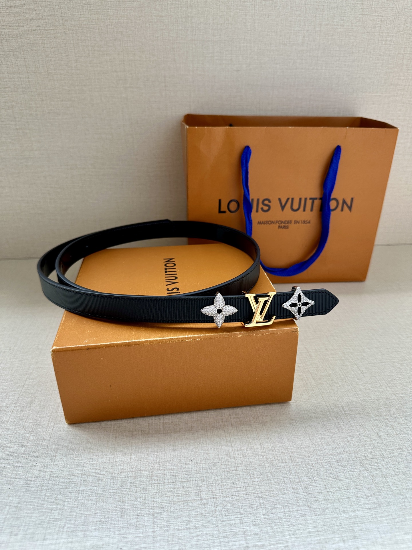  2.0宽 LV Trio 双面腰带拼合细腻牛皮革和 Monogram 帆布，为中央金属搭扣聚焦 LV 
