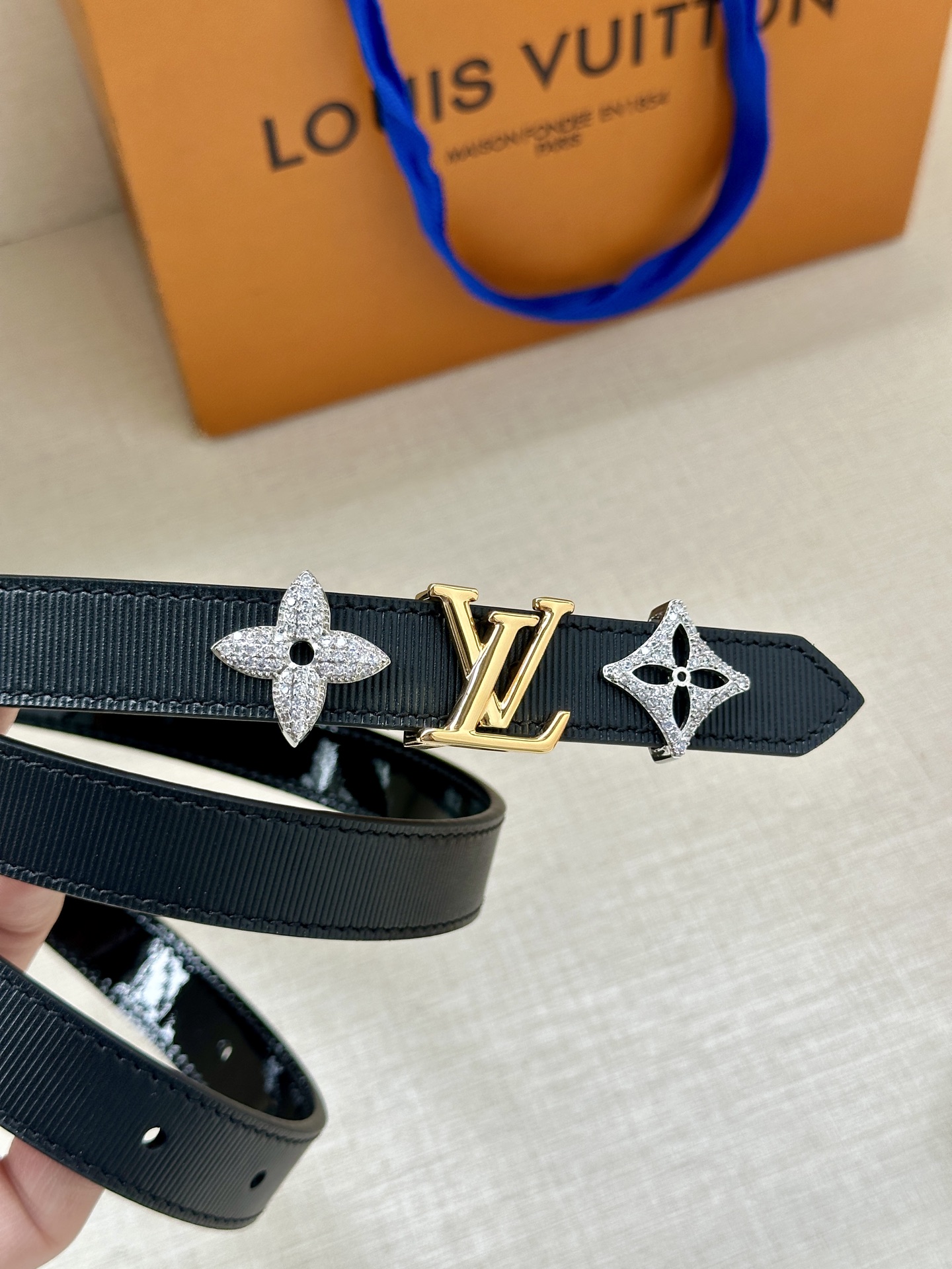  2.0宽 LV Trio 双面腰带拼合细腻牛皮革和 Monogram 帆布，为中央金属搭扣聚焦 LV 