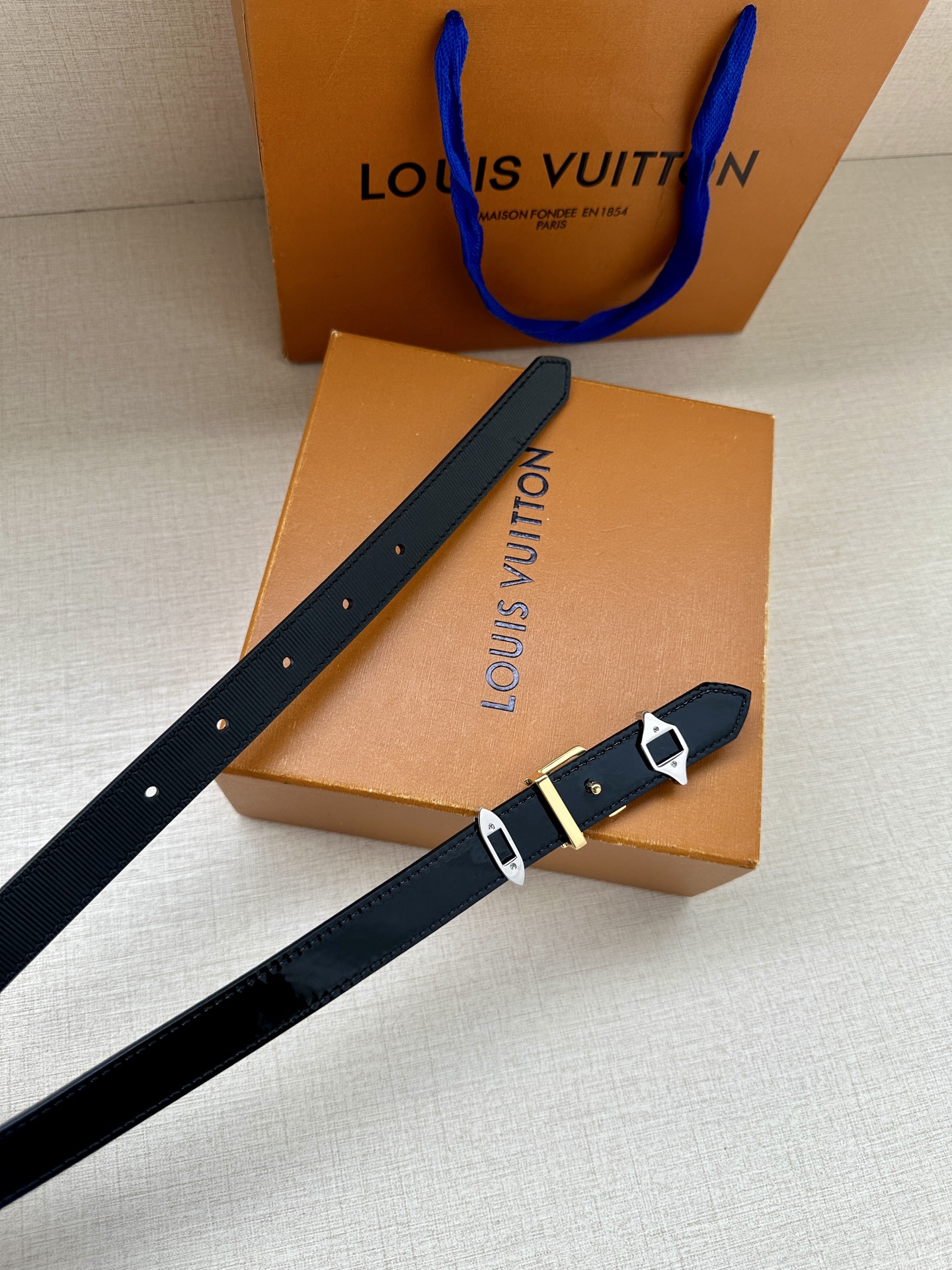  2.0宽 LV Trio 双面腰带拼合细腻牛皮革和 Monogram 帆布，为中央金属搭扣聚焦 LV 