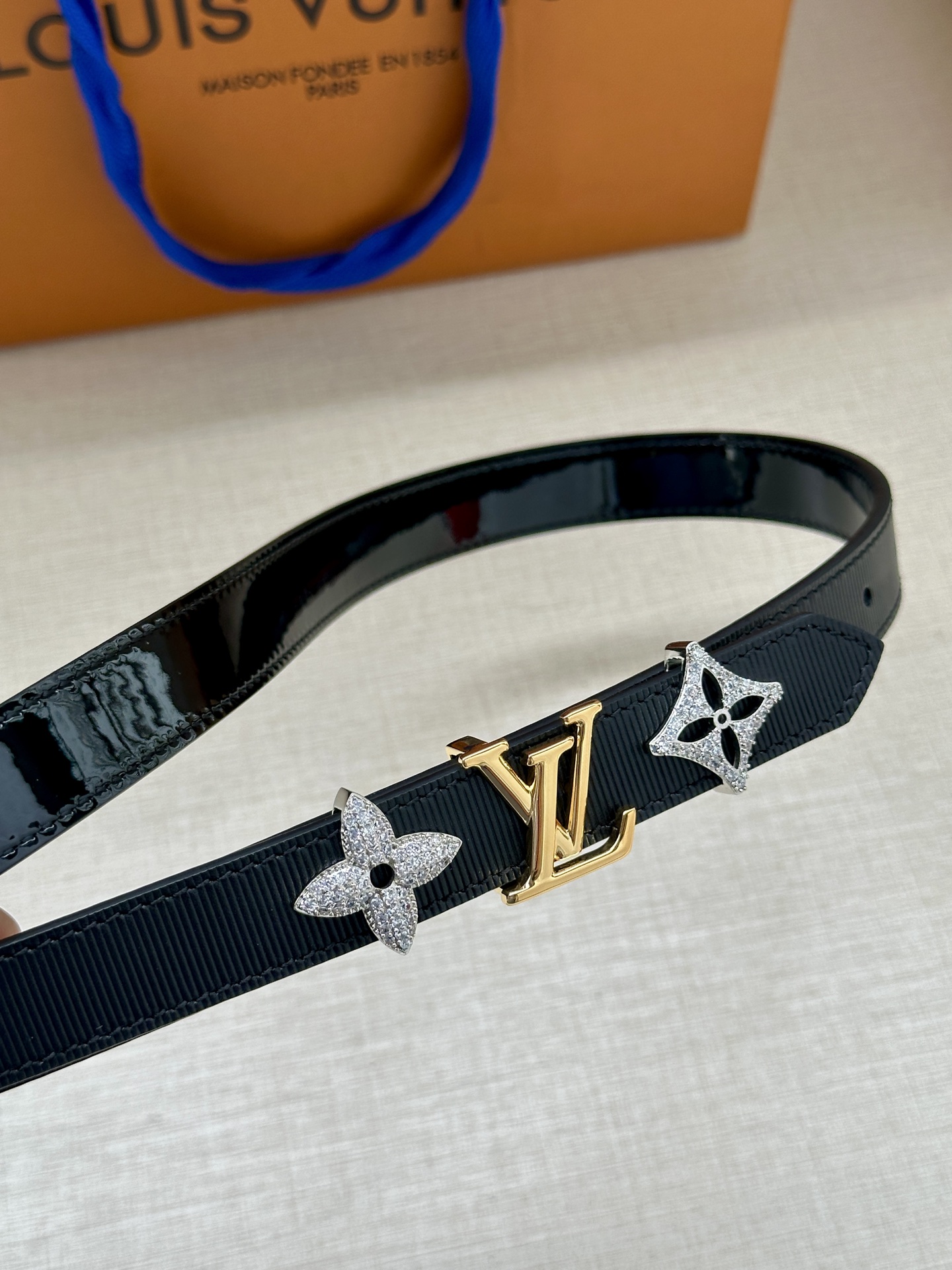  2.0宽 LV Trio 双面腰带拼合细腻牛皮革和 Monogram 帆布，为中央金属搭扣聚焦 LV 