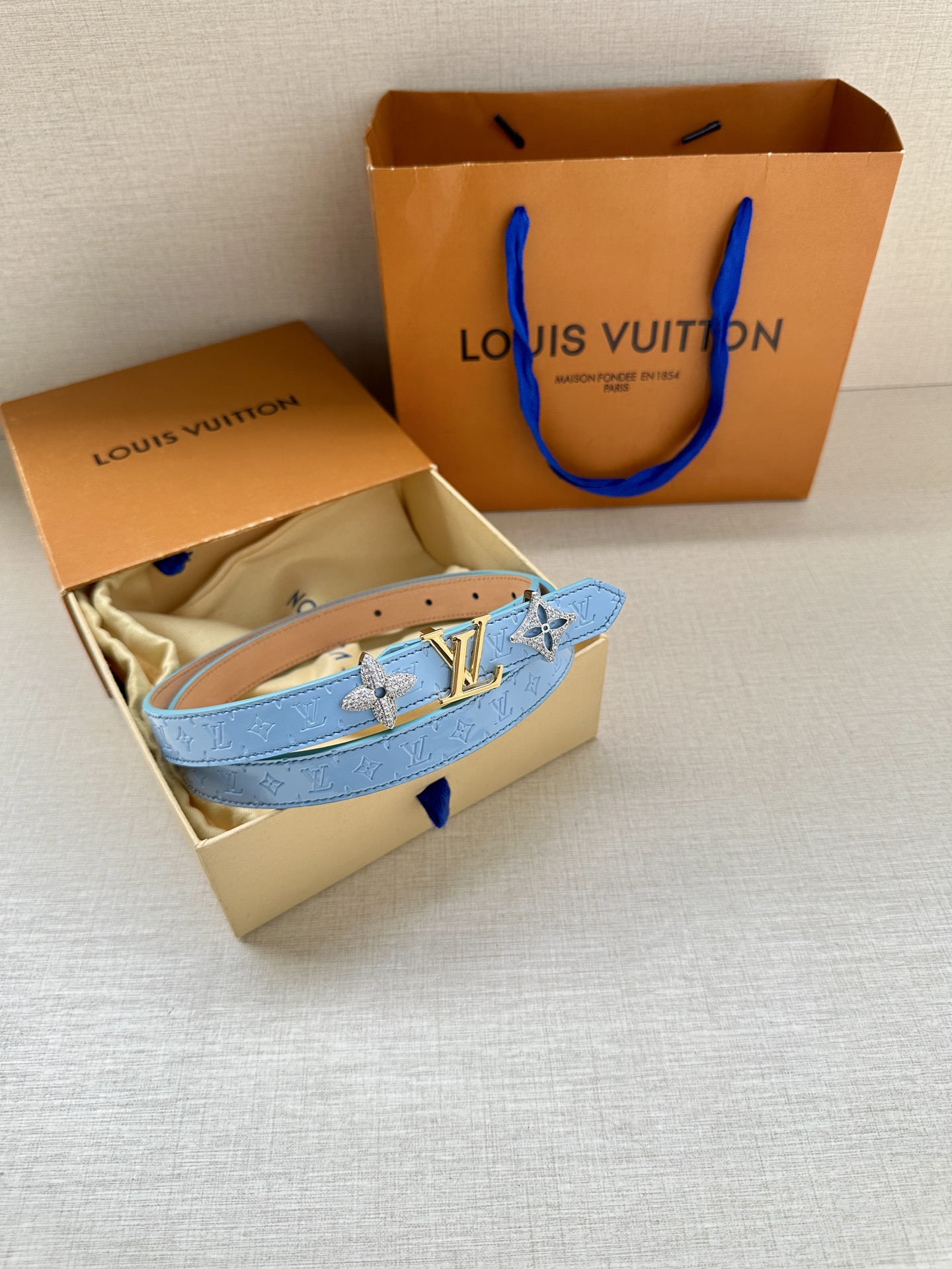  2.0宽 LV Trio 双面腰带拼合细腻牛皮革和 Monogram 帆布，为中央金属搭扣聚焦 LV 