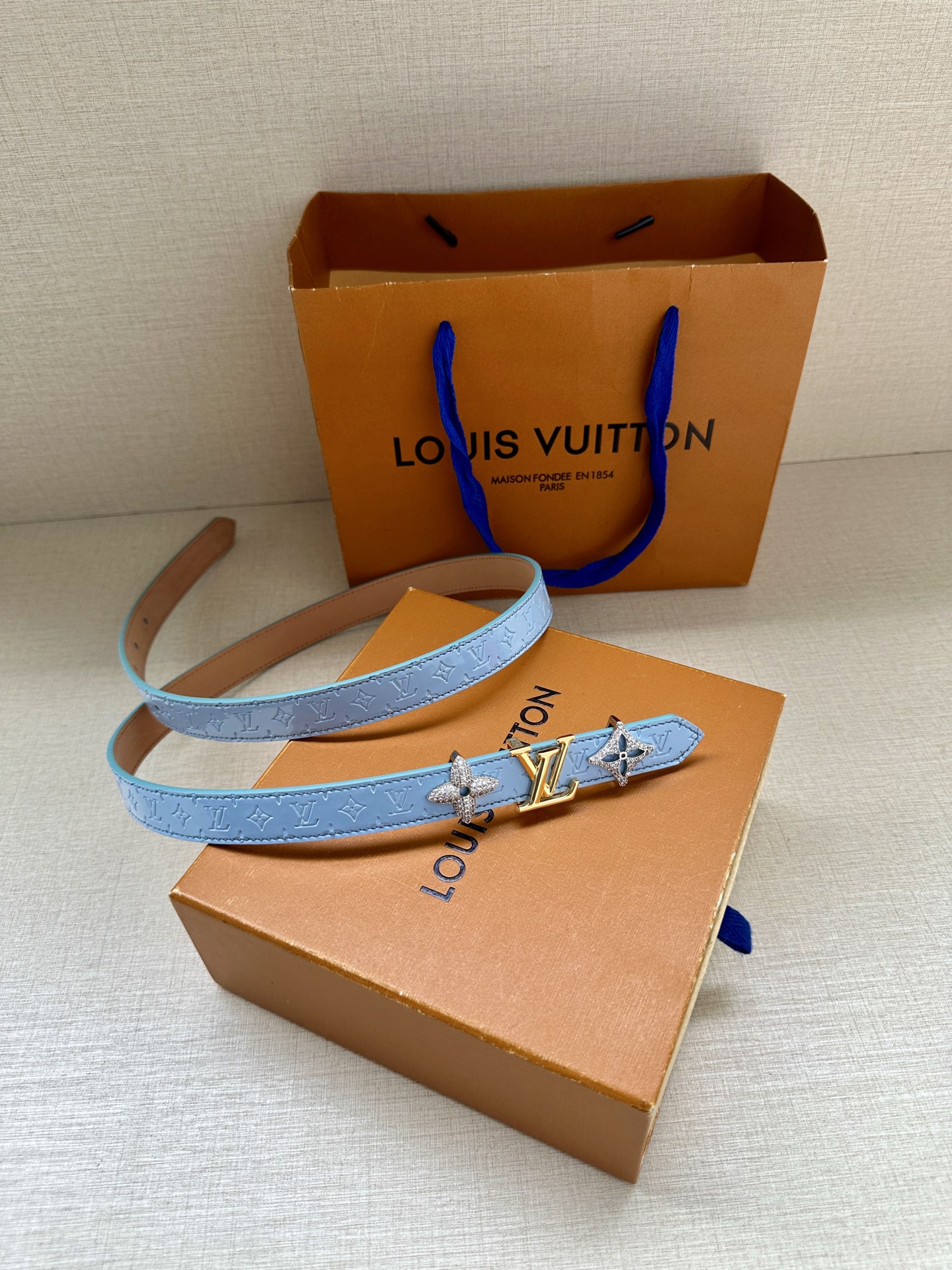  2.0宽 LV Trio 双面腰带拼合细腻牛皮革和 Monogram 帆布，为中央金属搭扣聚焦 LV 