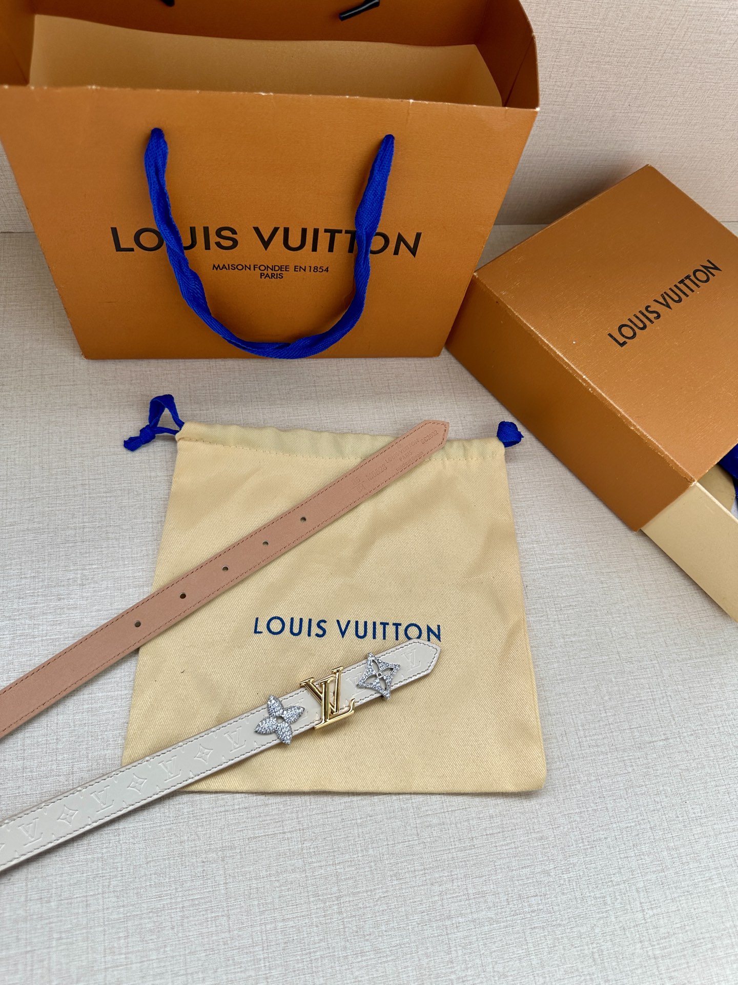 2.0宽 LV Trio 双面腰带拼合细腻牛皮革和 Monogram 帆布，为中央金属搭扣聚焦 LV 