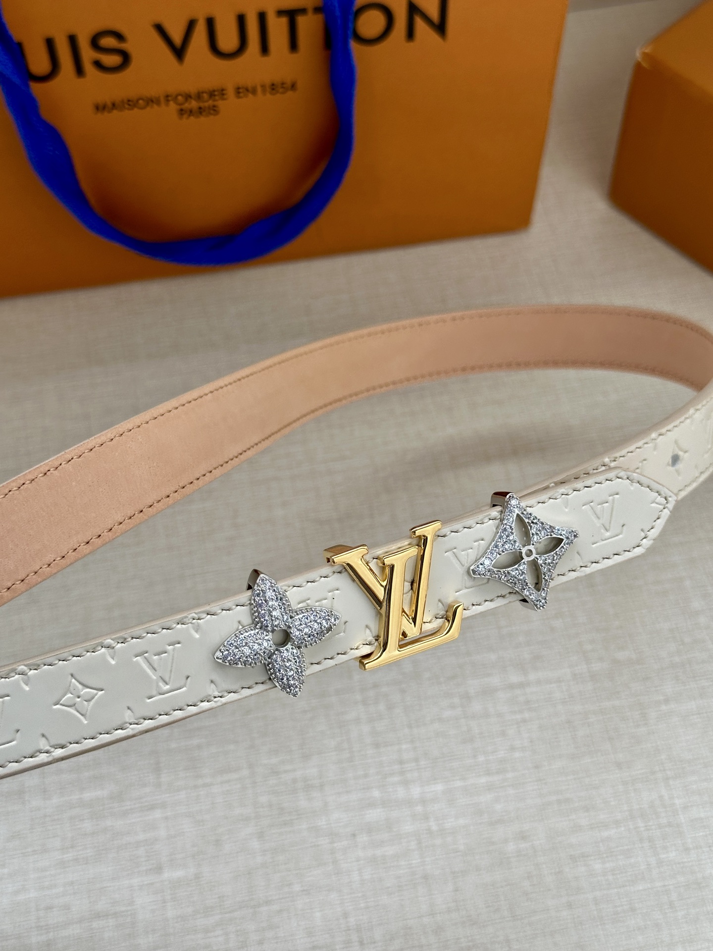  2.0宽 LV Trio 双面腰带拼合细腻牛皮革和 Monogram 帆布，为中央金属搭扣聚焦 LV 