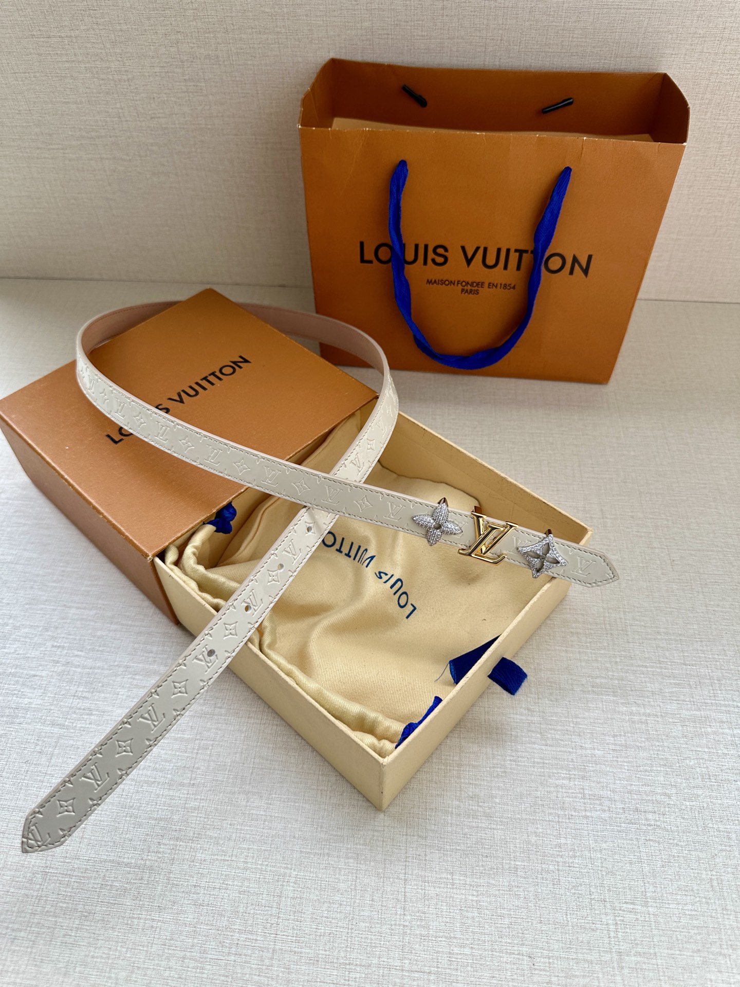  2.0宽 LV Trio 双面腰带拼合细腻牛皮革和 Monogram 帆布，为中央金属搭扣聚焦 LV 