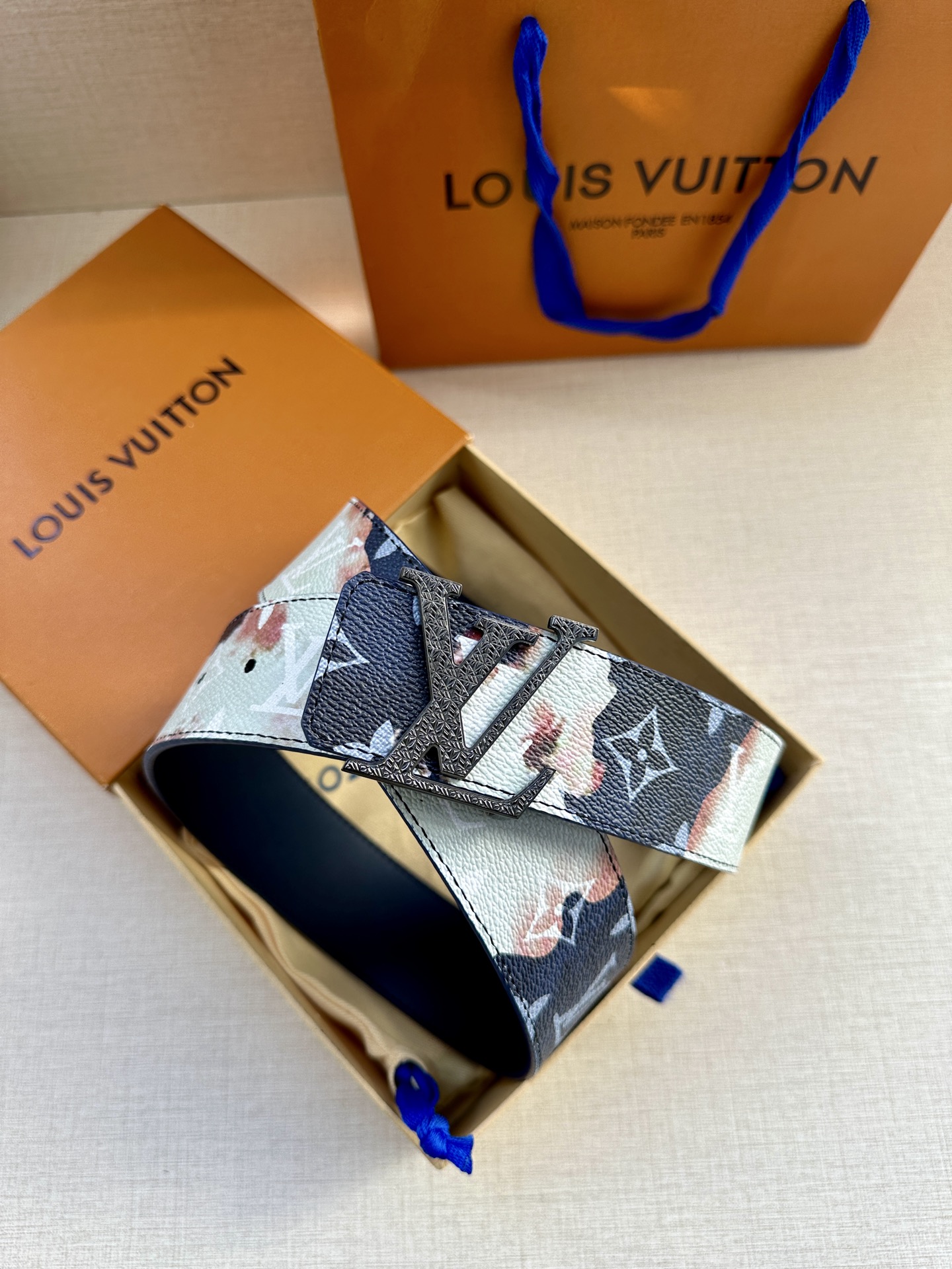  本款4.0宽LV Initials 双面腰带以醒目图案描摹烧焦的纸张，唤起对熊熊篝火和户外时光的回忆。