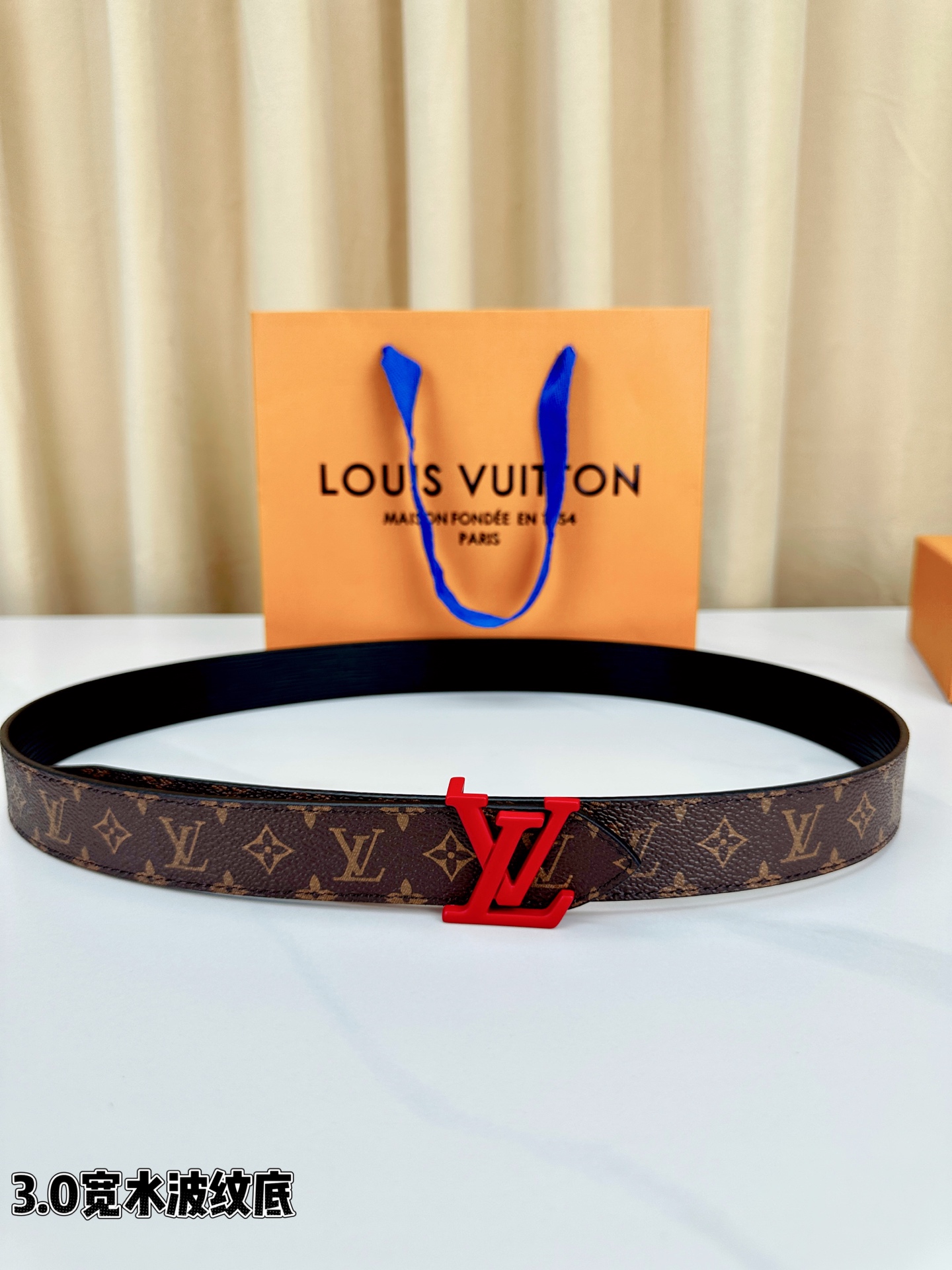 经典棕底水波纹压花邂逅亮眼红扣，3.0cm宽幅设计勾勒腰线。LV标志性字母扣点缀，皮革触感细腻。1854