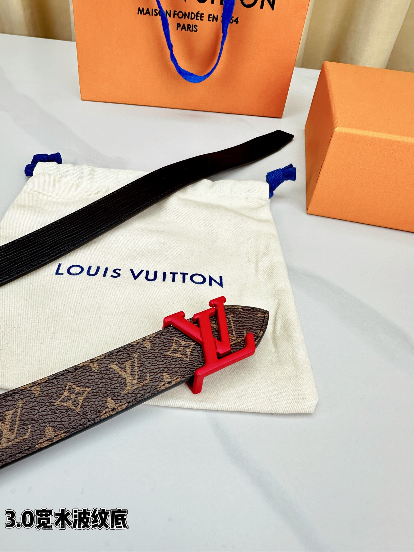 经典棕底水波纹压花邂逅亮眼红扣，3.0cm宽幅设计勾勒腰线。LV标志性字母扣点缀，皮革触感细腻。1854