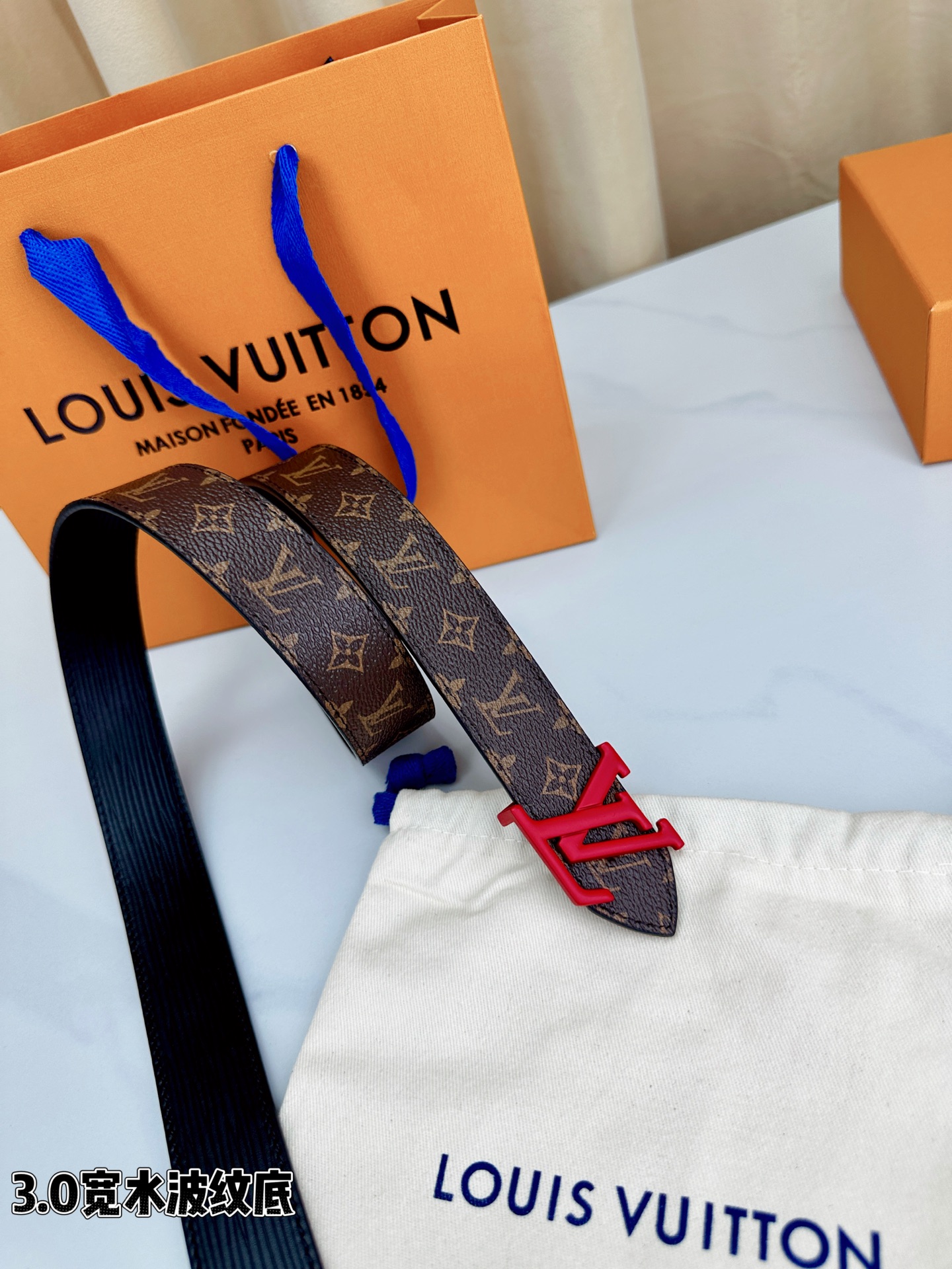 经典棕底水波纹压花邂逅亮眼红扣，3.0cm宽幅设计勾勒腰线。LV标志性字母扣点缀，皮革触感细腻。1854