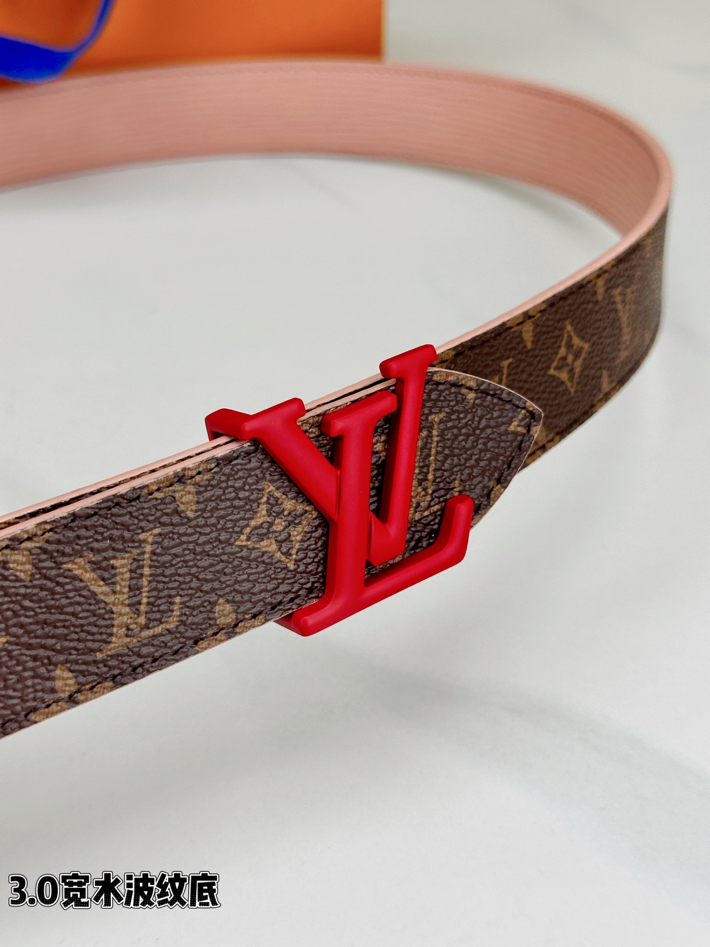 经典棕底水波纹压花邂逅亮眼红扣，3.0cm宽幅设计勾勒腰线。LV标志性字母扣点缀，皮革触感细腻。1854