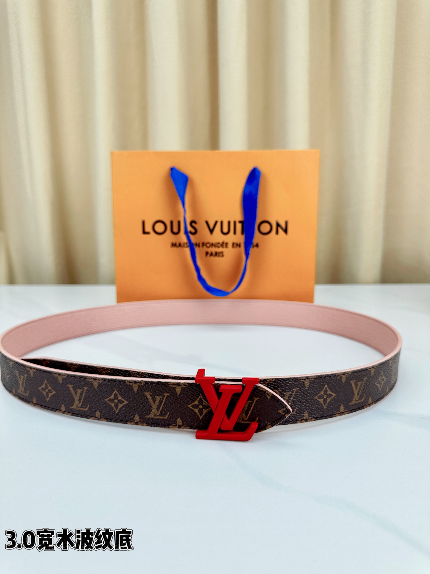 经典棕底水波纹压花邂逅亮眼红扣，3.0cm宽幅设计勾勒腰线。LV标志性字母扣点缀，皮革触感细腻。1854