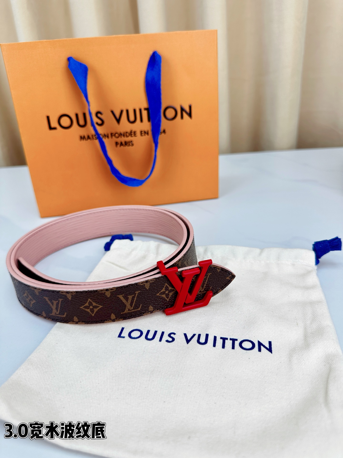 经典棕底水波纹压花邂逅亮眼红扣，3.0cm宽幅设计勾勒腰线。LV标志性字母扣点缀，皮革触感细腻。1854