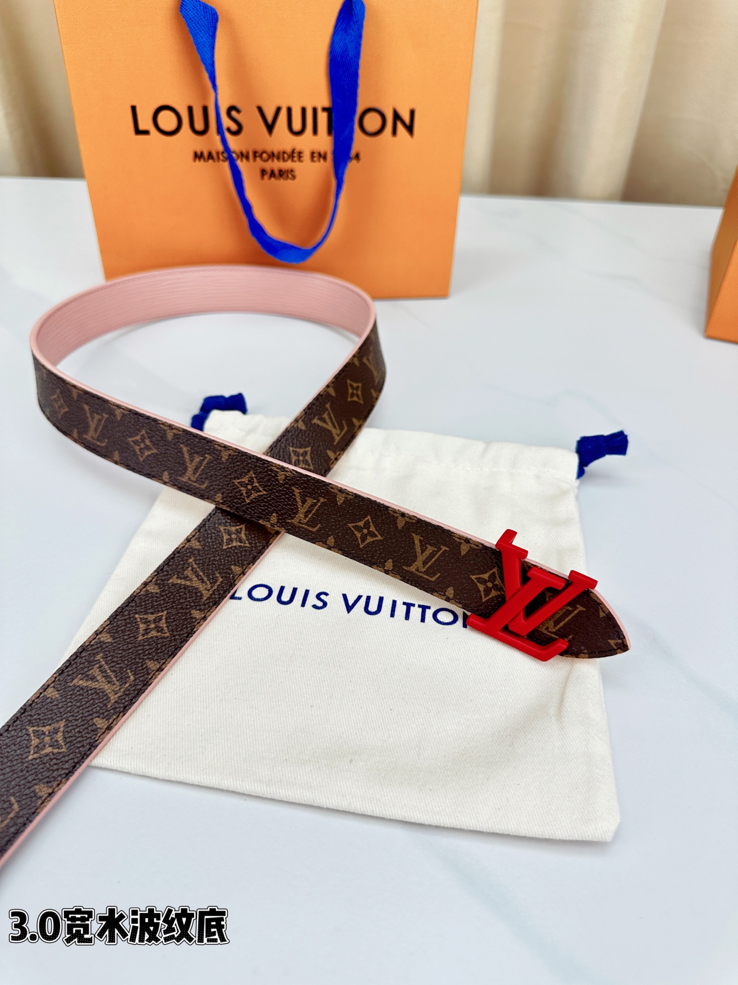 经典棕底水波纹压花邂逅亮眼红扣，3.0cm宽幅设计勾勒腰线。LV标志性字母扣点缀，皮革触感细腻。1854