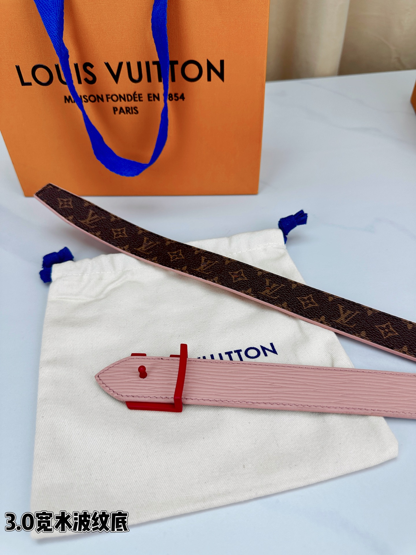 经典棕底水波纹压花邂逅亮眼红扣，3.0cm宽幅设计勾勒腰线。LV标志性字母扣点缀，皮革触感细腻。1854