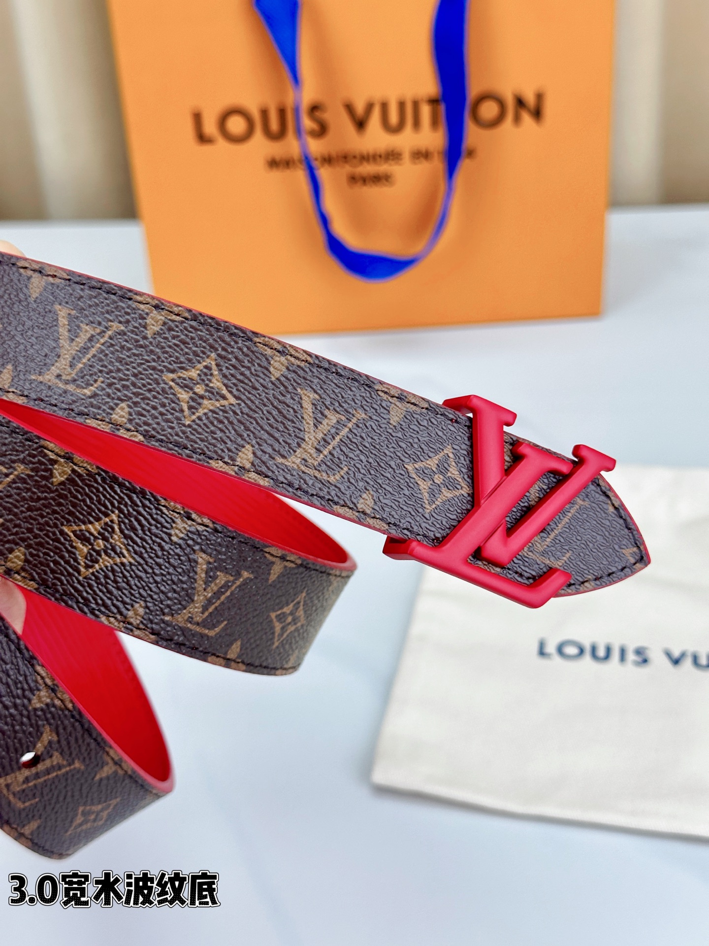经典棕底水波纹压花邂逅亮眼红扣，3.0cm宽幅设计勾勒腰线。LV标志性字母扣点缀，皮革触感细腻。1854