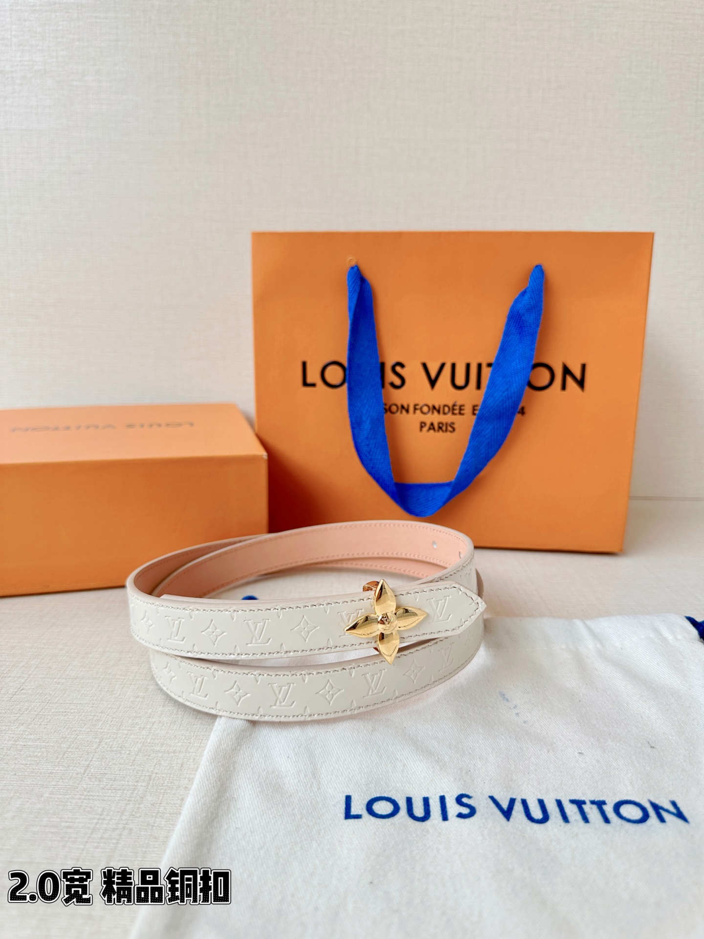 浅蓝色与米白色压纹皮革交织，2.0厘米纤细宽度勾勒腰线。金色铜质四叶花扣头，镌刻经典LV字母与菱形暗纹，