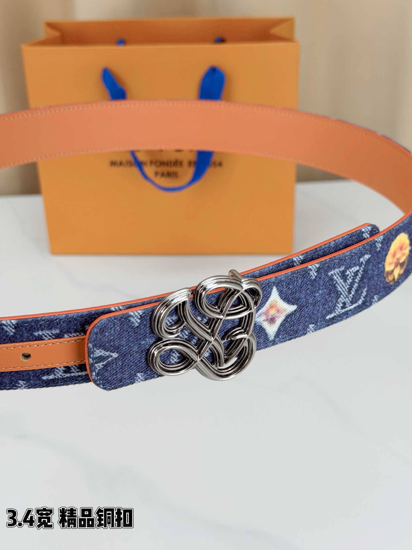 路易威登3.4宽腰带，深蓝牛仔肌理缀以橙黄花朵印花，法式浪漫悄然绽放。镂空铜扣线条交织，金银古白 古金 