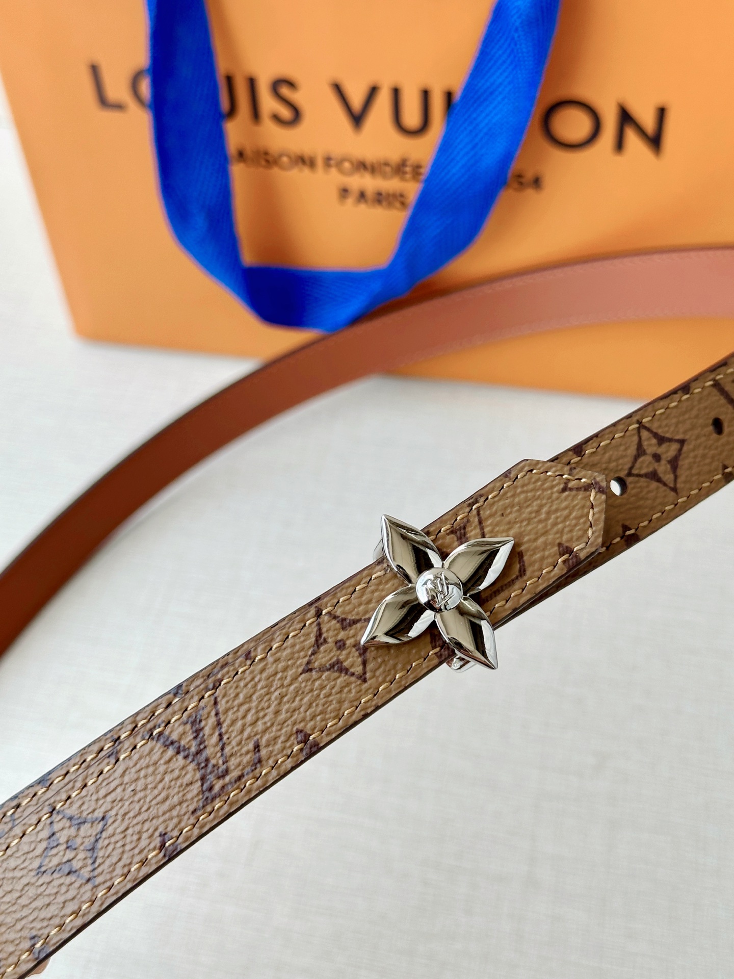 路易威登2.0宽精品铜扣老花腰带，经典老花邂逅四叶花扣，光影流转间熠熠生辉。深棕底色与浅金LV印记交织，