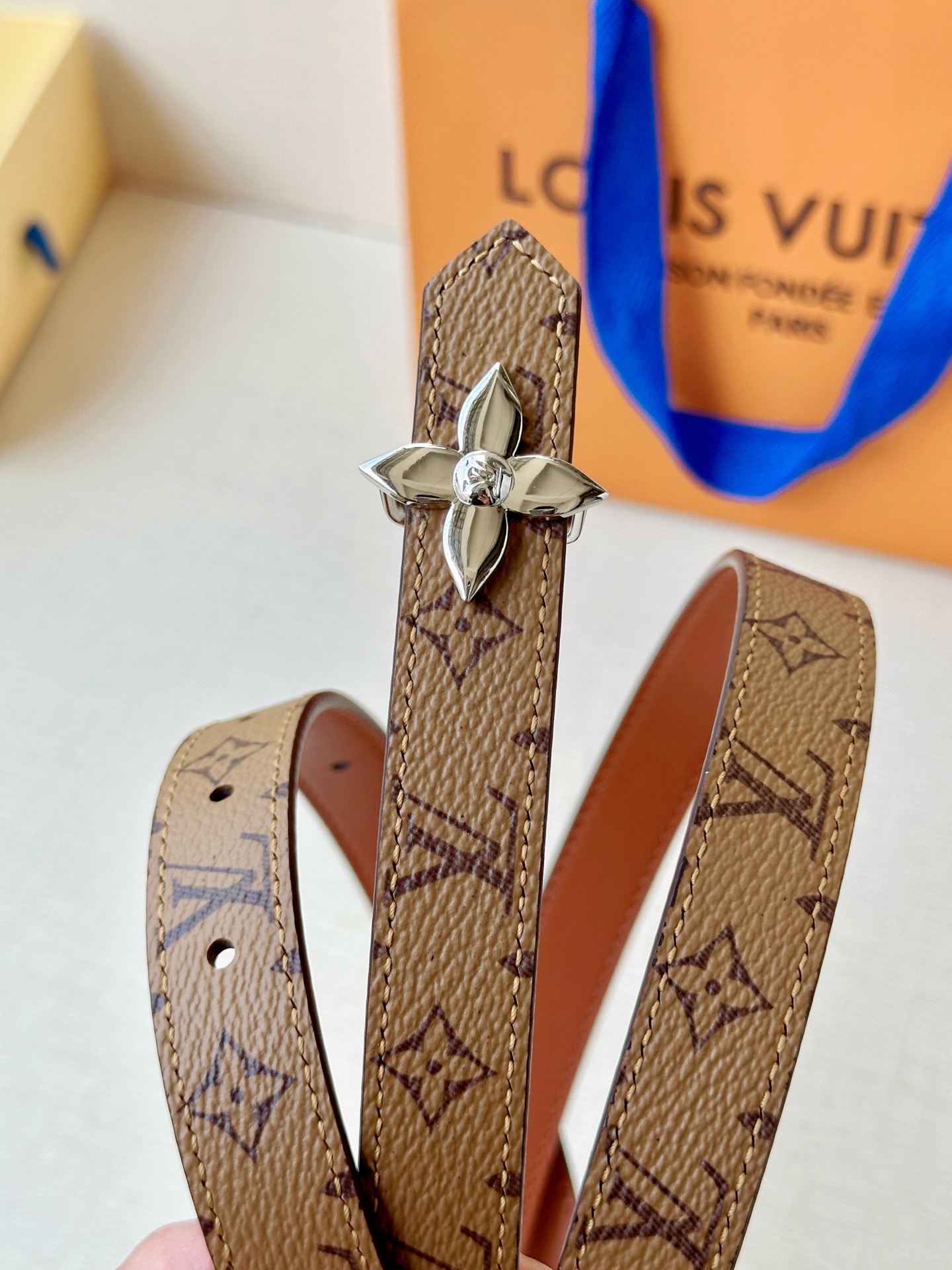 路易威登2.0宽精品铜扣老花腰带，经典老花邂逅四叶花扣，光影流转间熠熠生辉。深棕底色与浅金LV印记交织，