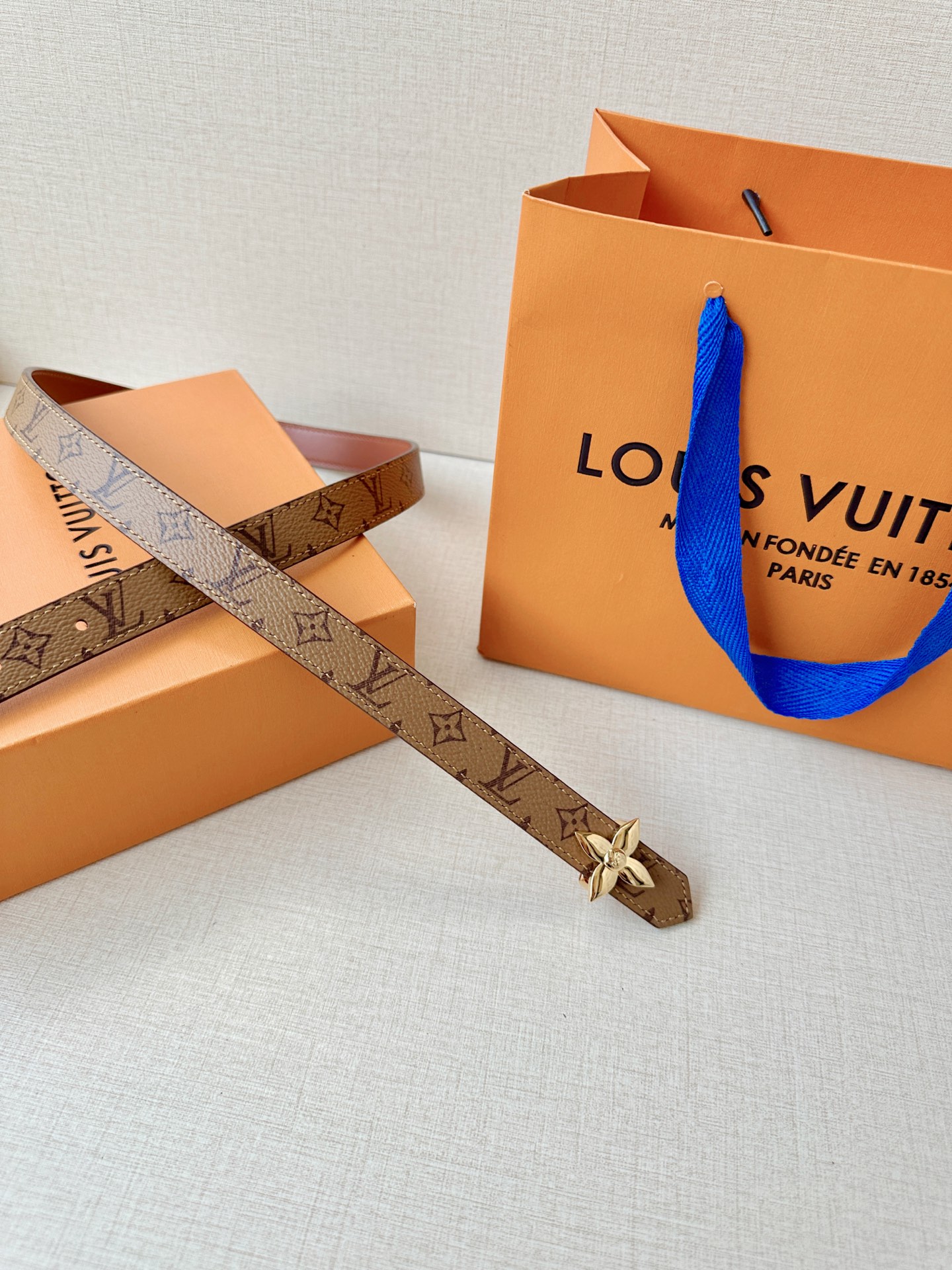 路易威登2.0宽精品铜扣老花腰带，经典老花邂逅四叶花扣，光影流转间熠熠生辉。深棕底色与浅金LV印记交织，