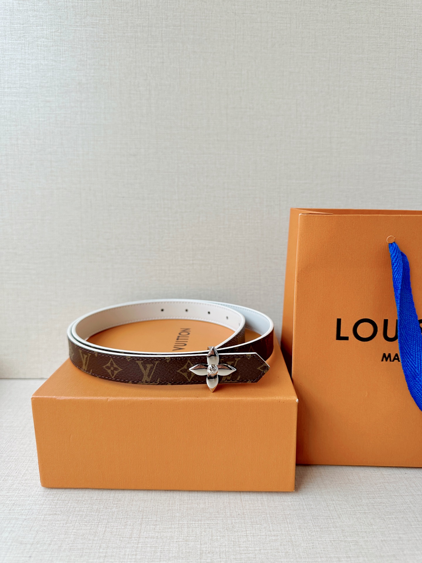路易威登2.0宽精品铜扣老花腰带，经典老花邂逅四叶花扣，光影流转间熠熠生辉。深棕底色与浅金LV印记交织，