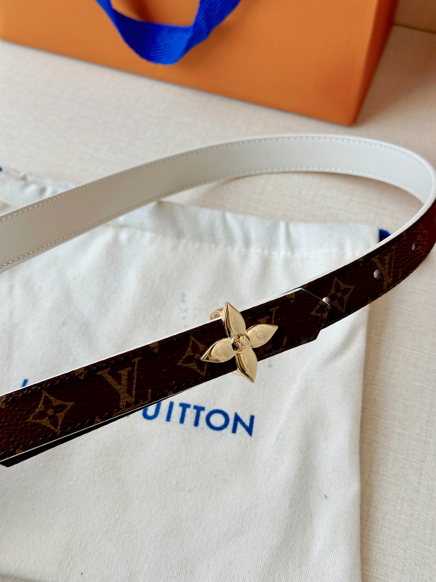 路易威登2.0宽精品铜扣老花腰带，经典老花邂逅四叶花扣，光影流转间熠熠生辉。深棕底色与浅金LV印记交织，