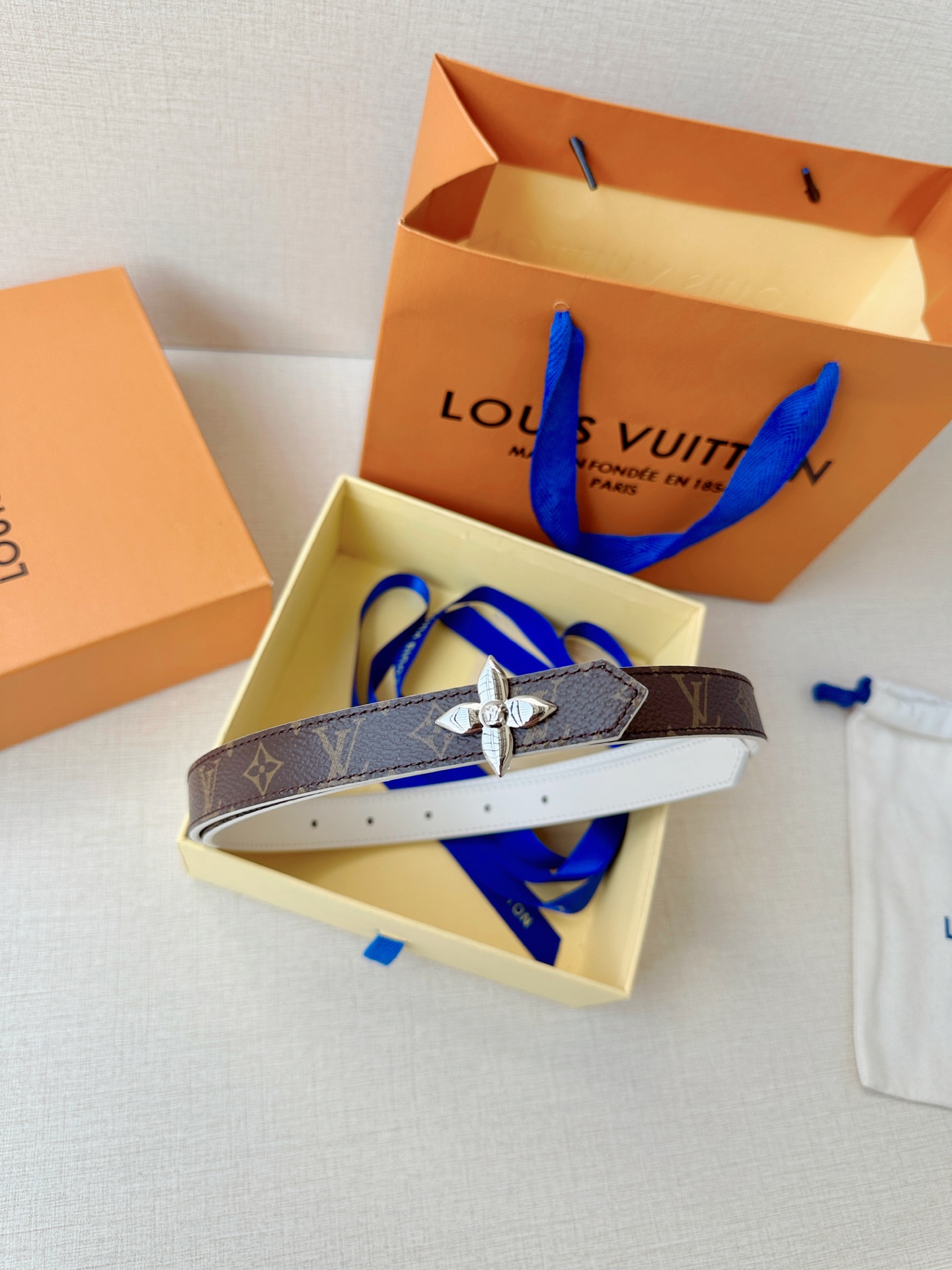 路易威登2.0宽精品铜扣老花腰带，经典老花邂逅四叶花扣，光影流转间熠熠生辉。深棕底色与浅金LV印记交织，