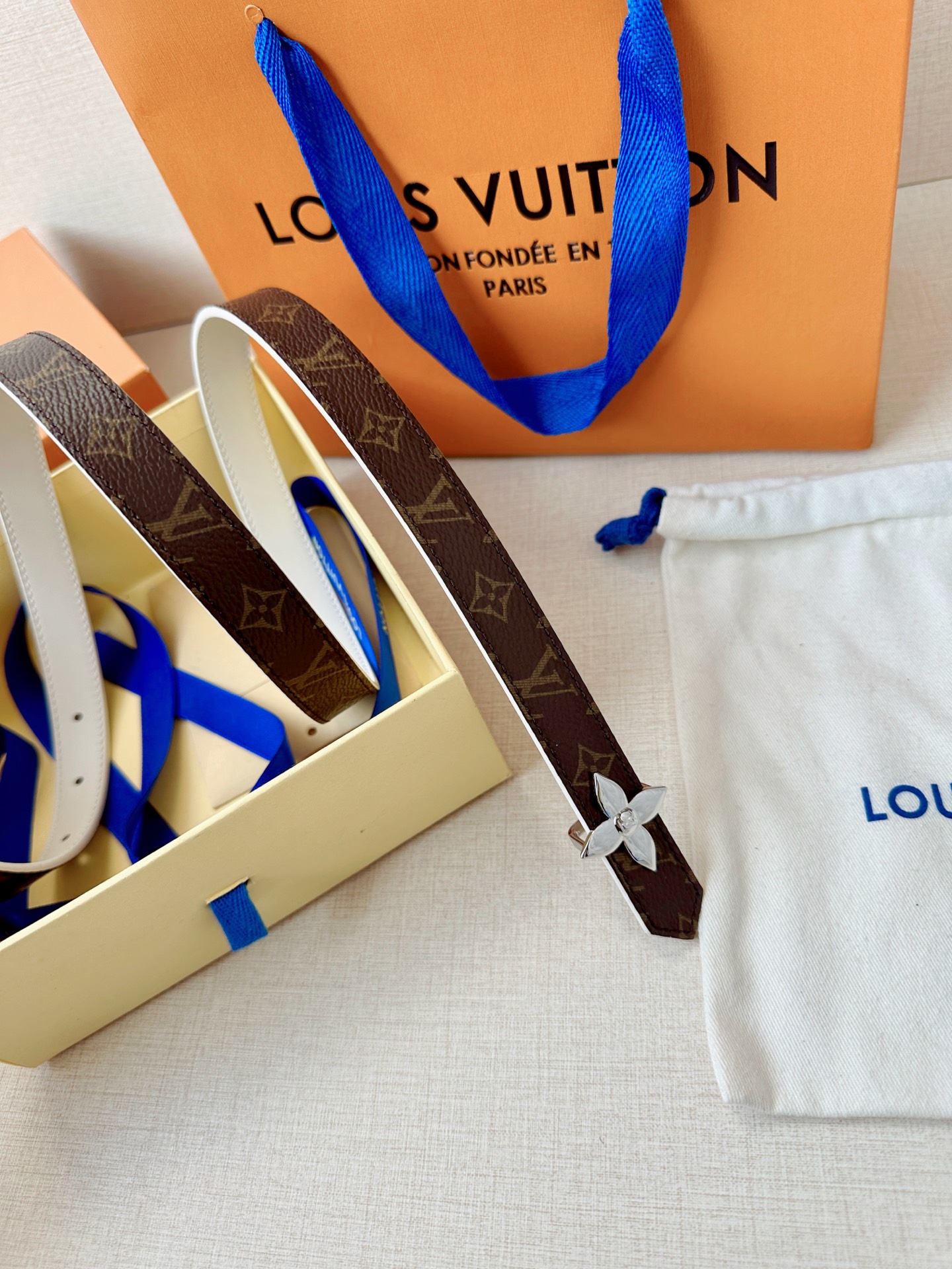 路易威登2.0宽精品铜扣老花腰带，经典老花邂逅四叶花扣，光影流转间熠熠生辉。深棕底色与浅金LV印记交织，