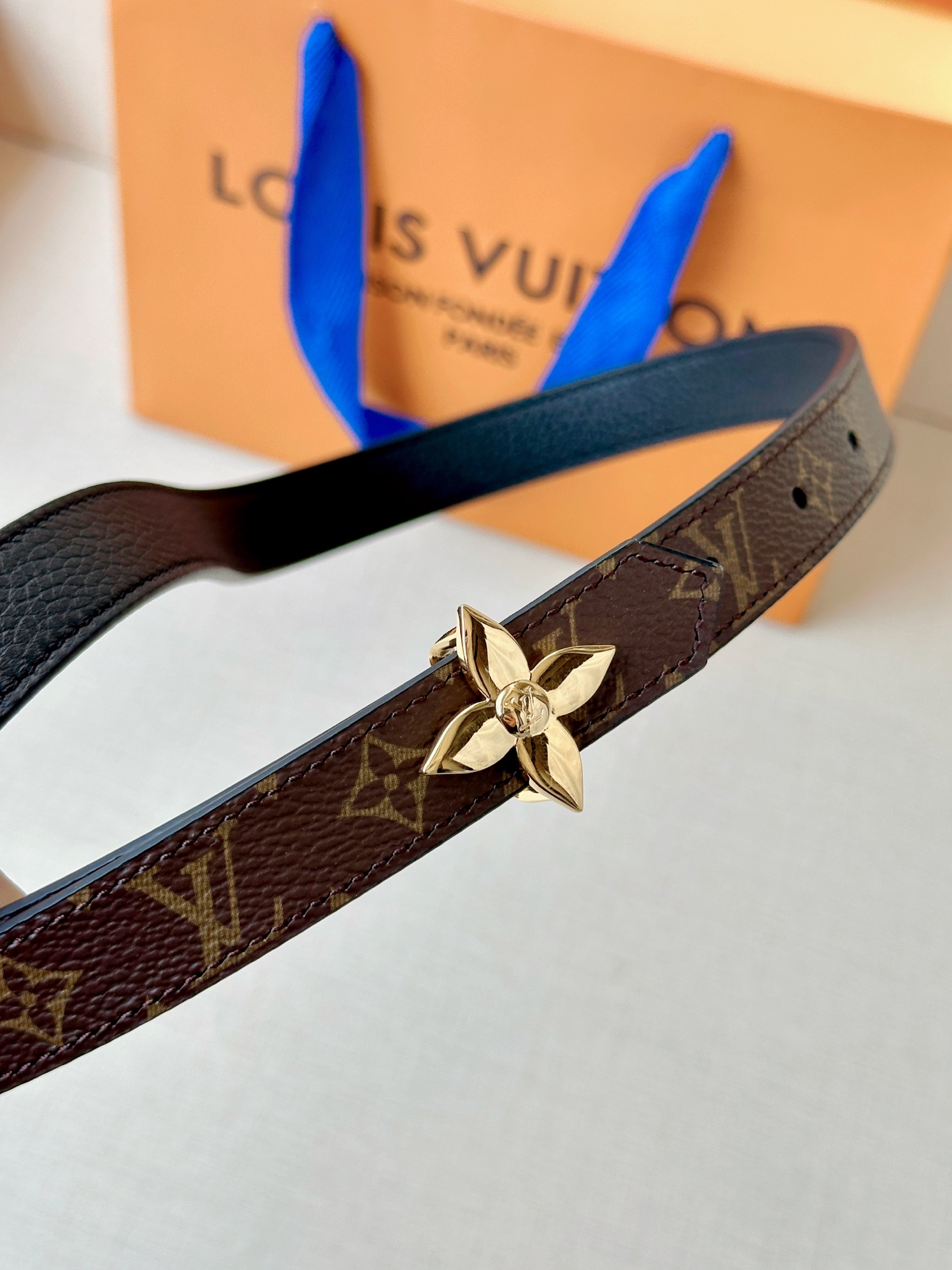 路易威登2.0宽精品铜扣老花腰带，经典老花邂逅四叶花扣，光影流转间熠熠生辉。深棕底色与浅金LV印记交织，
