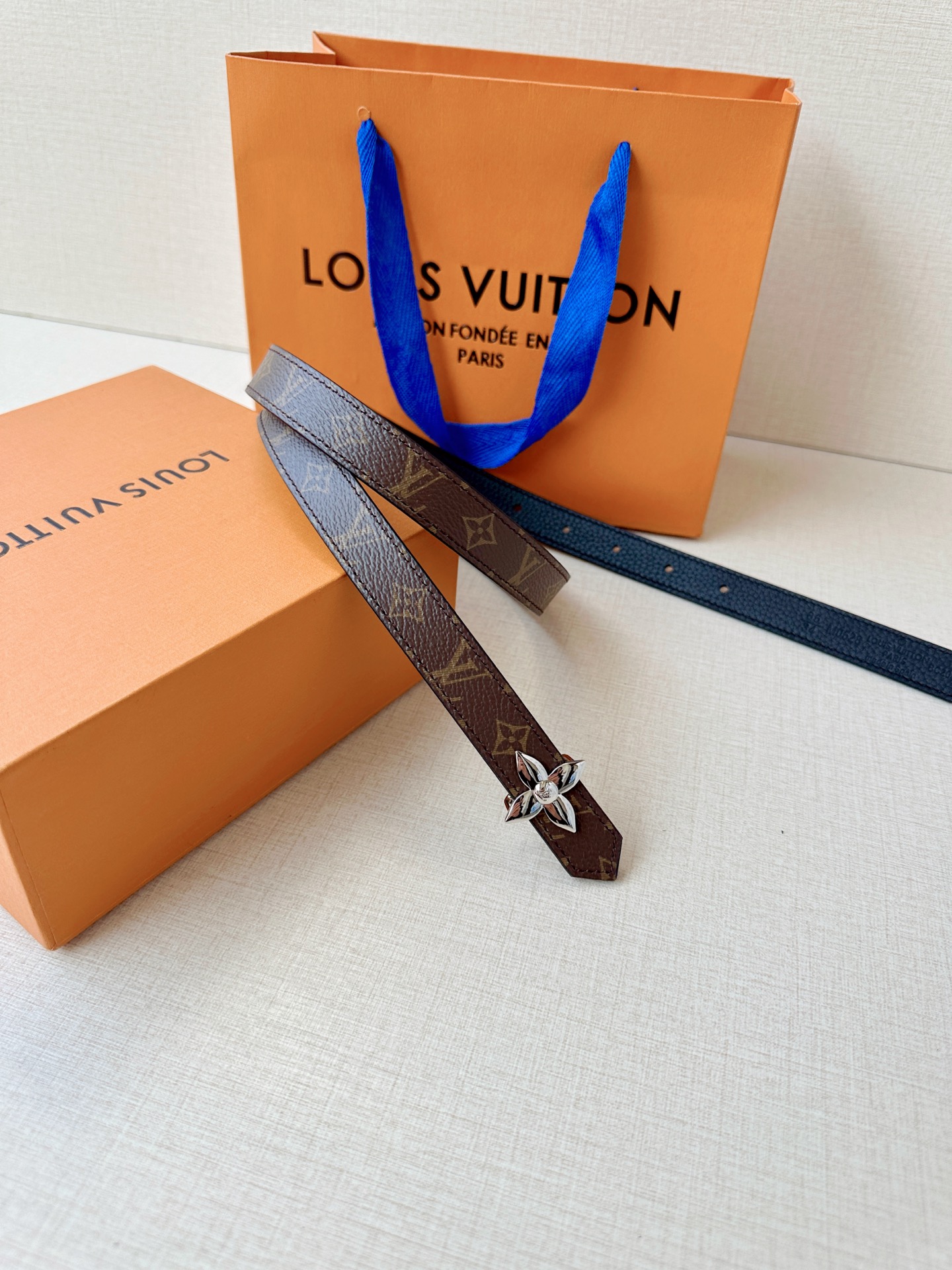 路易威登2.0宽精品铜扣老花腰带，经典老花邂逅四叶花扣，光影流转间熠熠生辉。深棕底色与浅金LV印记交织，