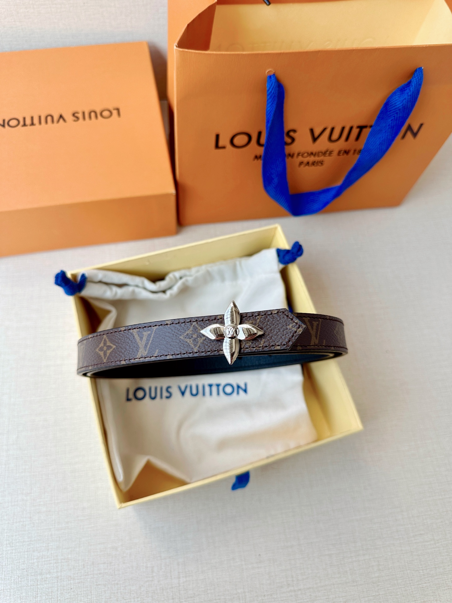 路易威登2.0宽精品铜扣老花腰带，经典老花邂逅四叶花扣，光影流转间熠熠生辉。深棕底色与浅金LV印记交织，