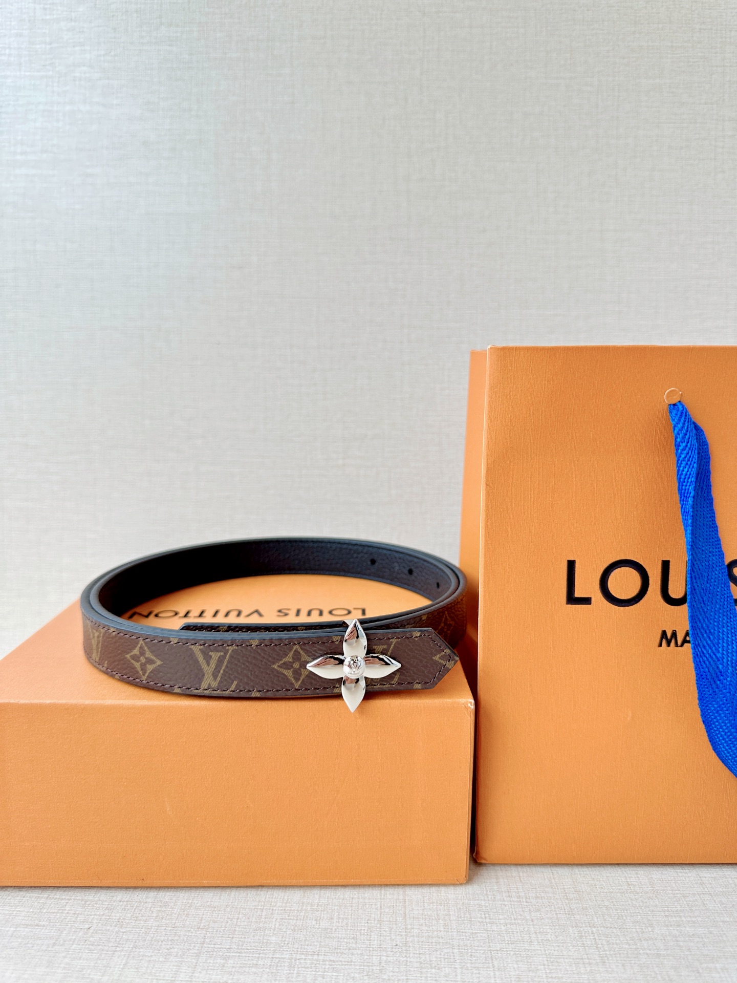 路易威登2.0宽精品铜扣老花腰带，经典老花邂逅四叶花扣，光影流转间熠熠生辉。深棕底色与浅金LV印记交织，