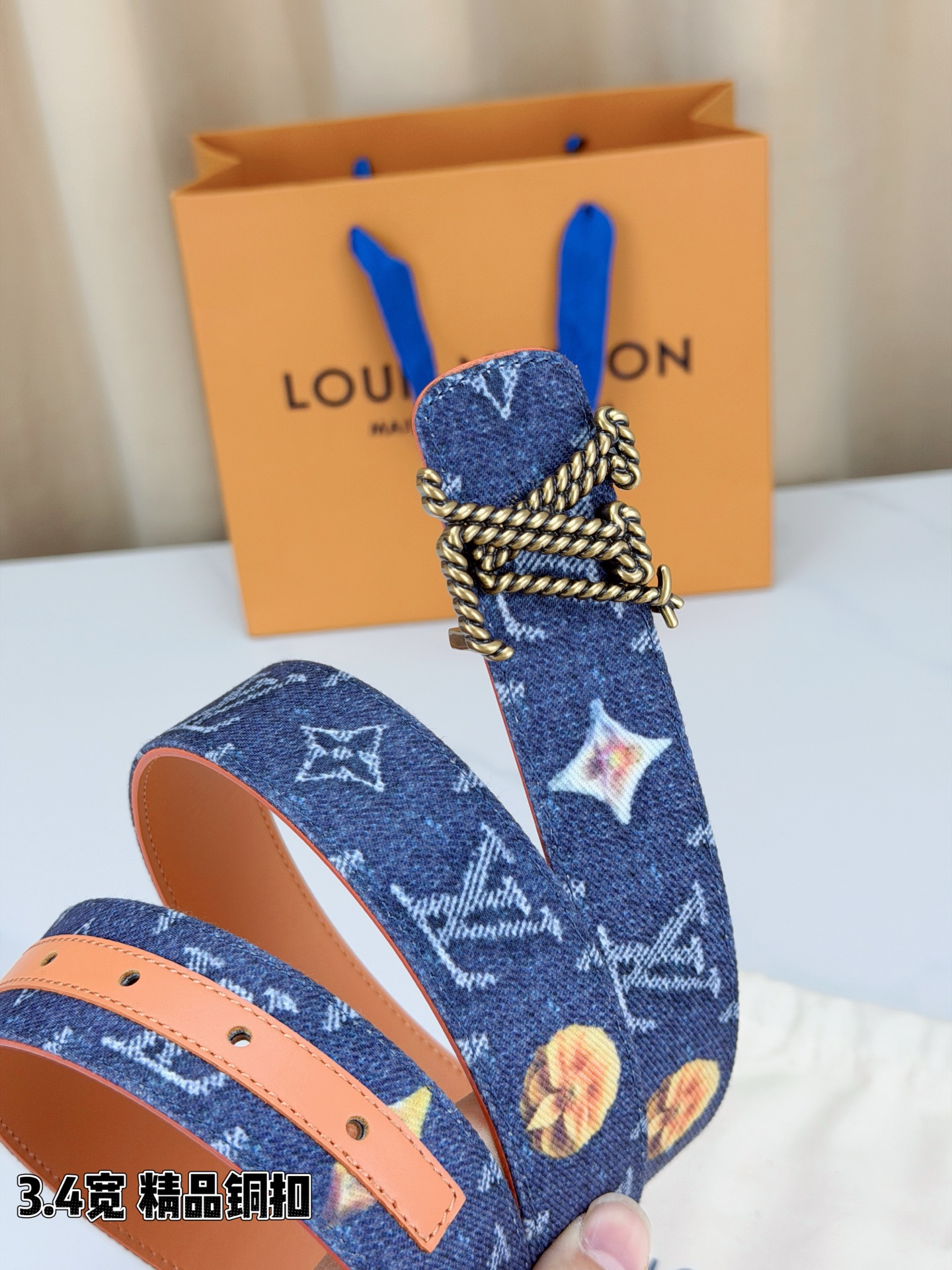 路易威登3.4宽精品铜扣腰带，深蓝牛仔邂逅暖橙皮革，双面风情随心切换。金色扭绳LV扣熠熠生辉，银链V形扣