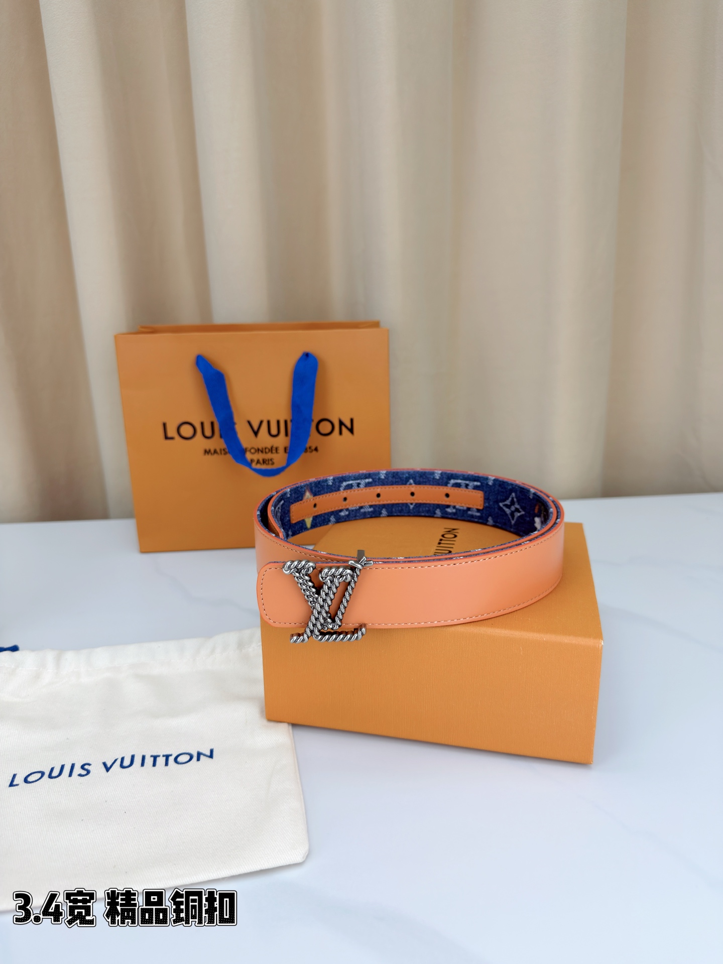 路易威登3.4宽精品铜扣腰带，深蓝牛仔邂逅暖橙皮革，双面风情随心切换。金色扭绳LV扣熠熠生辉，银链V形扣