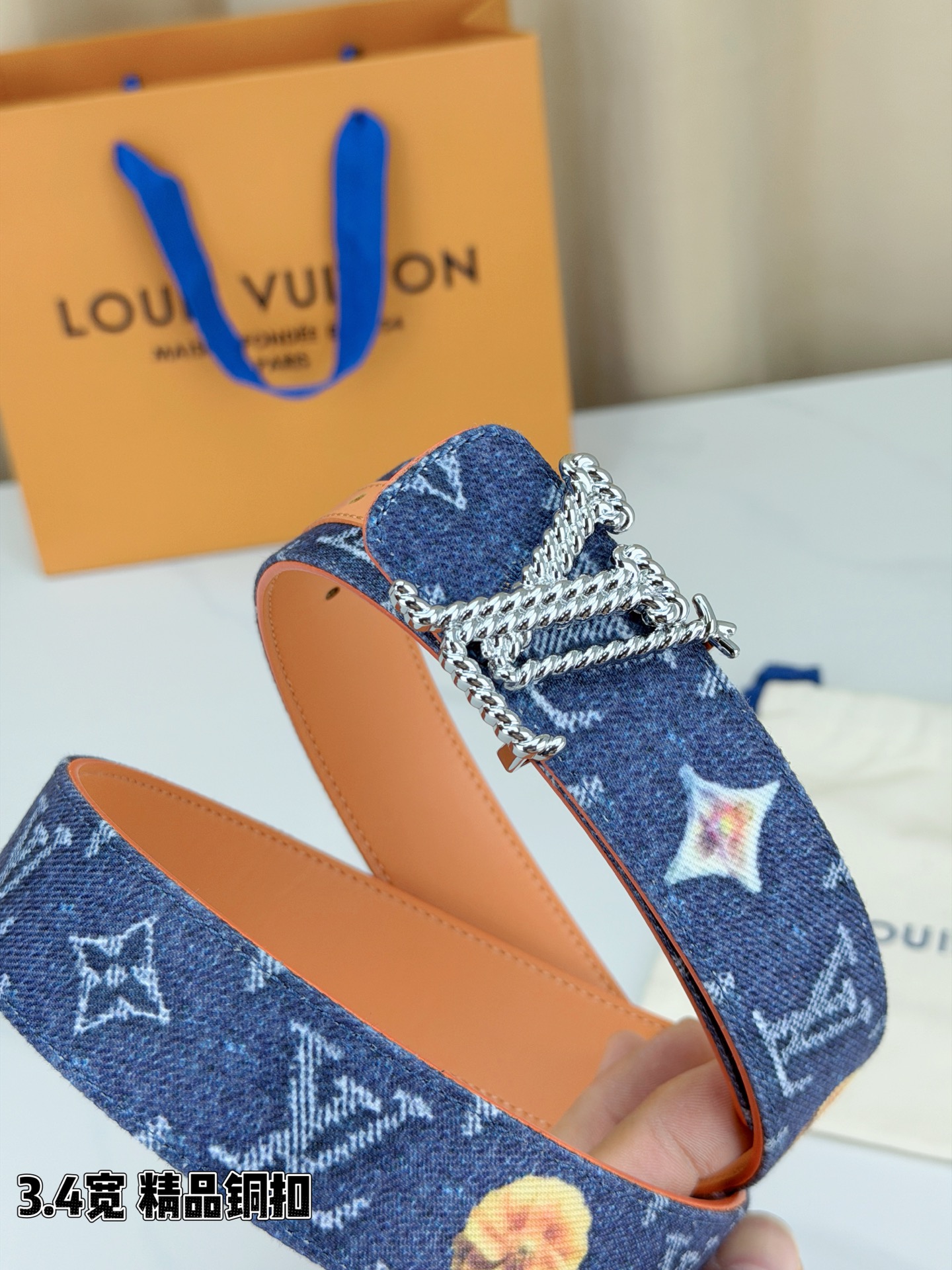 路易威登3.4宽精品铜扣腰带，深蓝牛仔邂逅暖橙皮革，双面风情随心切换。金色扭绳LV扣熠熠生辉，银链V形扣