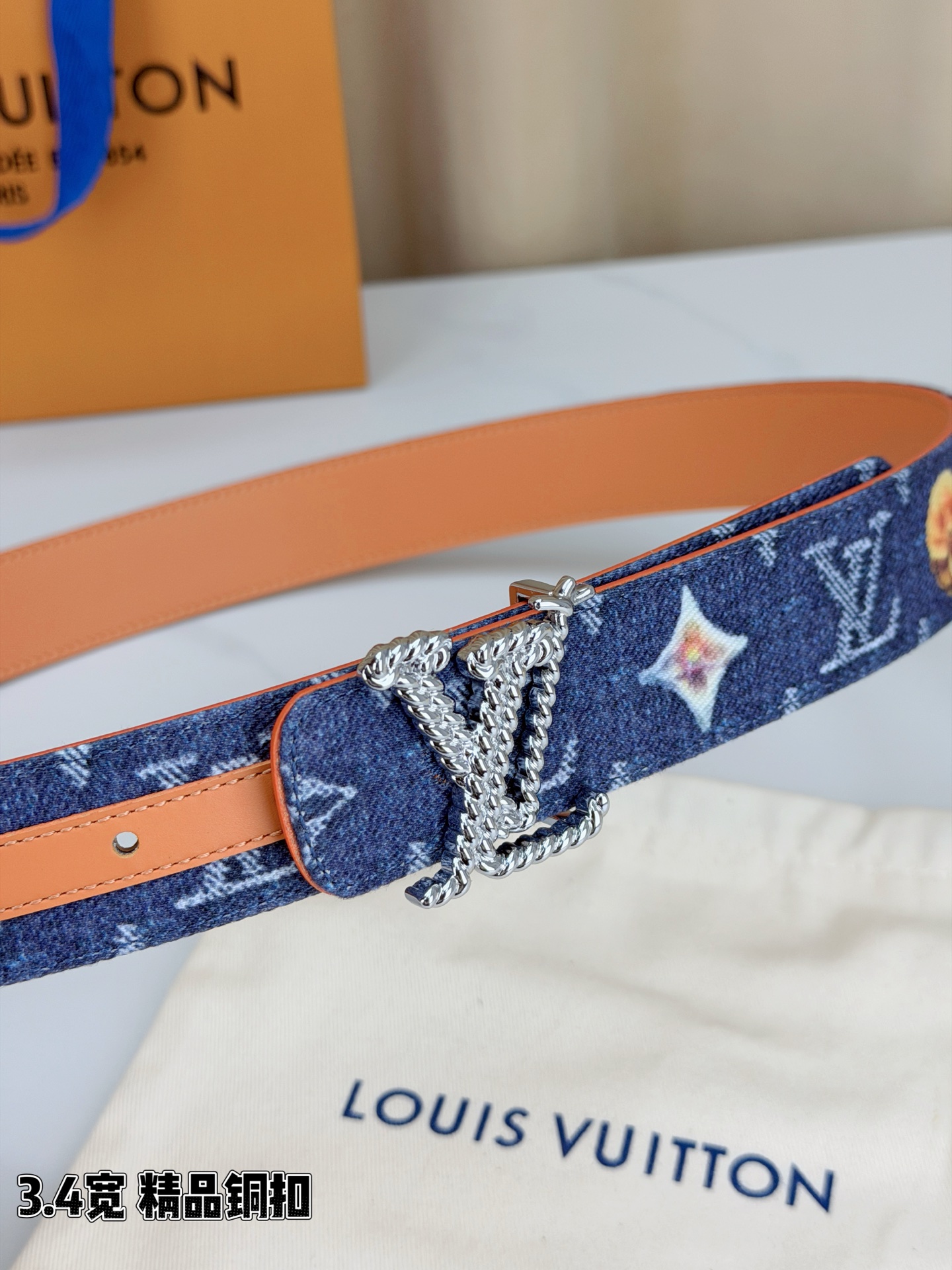 路易威登3.4宽精品铜扣腰带，深蓝牛仔邂逅暖橙皮革，双面风情随心切换。金色扭绳LV扣熠熠生辉，银链V形扣