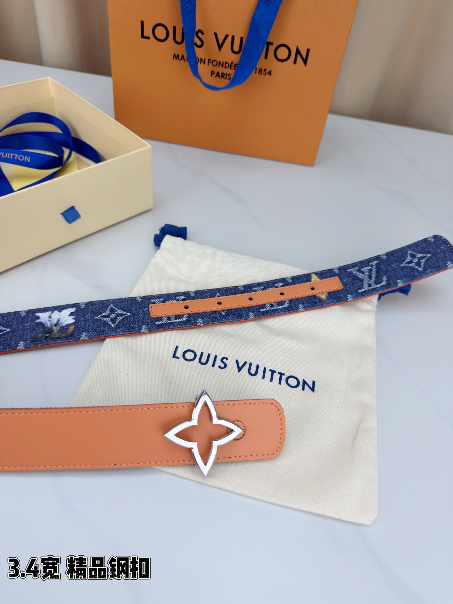 路易威登3.4宽精品钢扣腰带，深蓝牛仔邂逅经典老花，白色LV印记与浅橙花朵交相辉映。镂空四叶花扣金色华贵